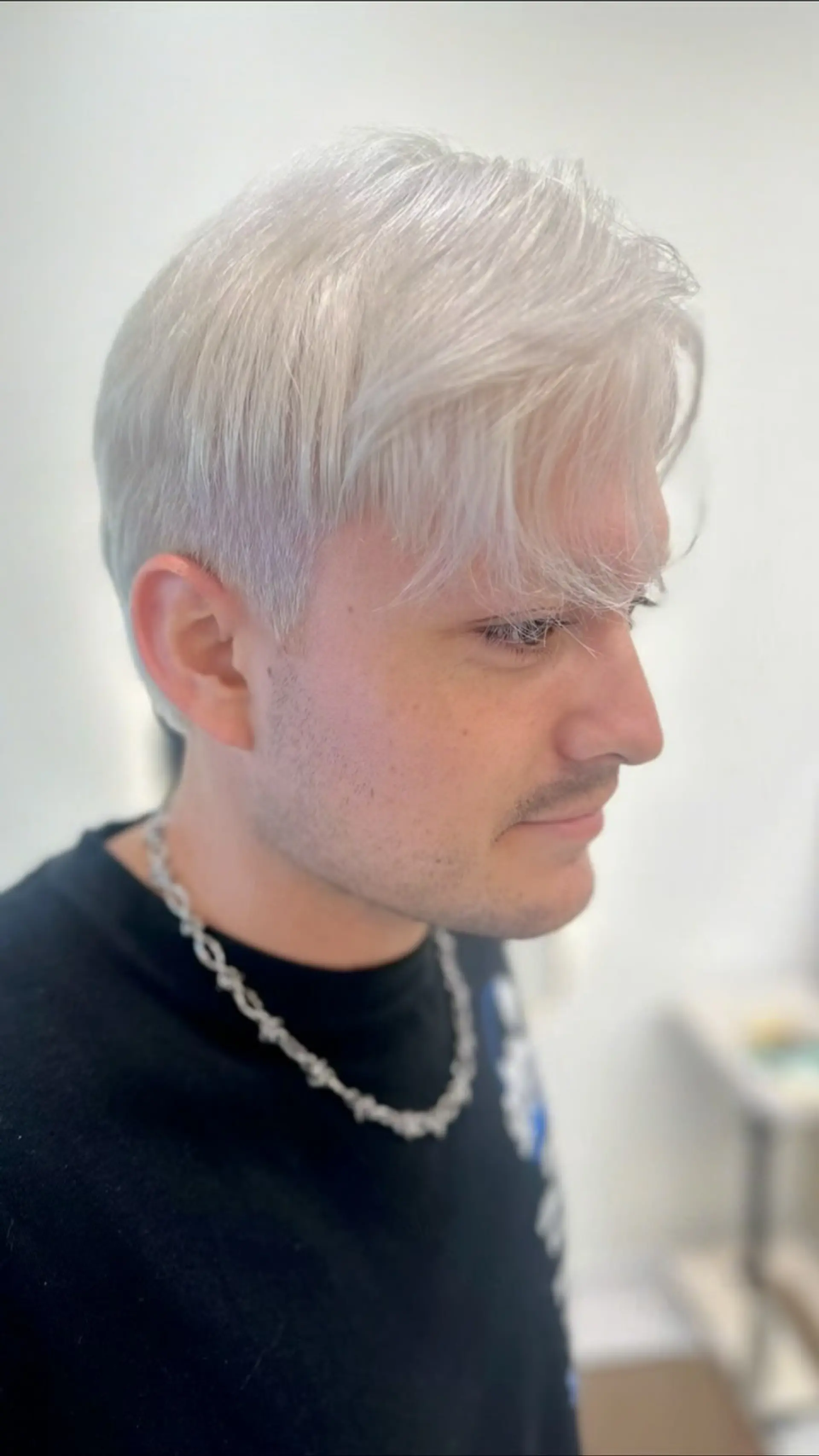 A short, textured crop cut featuring soft forward-swept fringe in a bright, cool platinum silver blonde. 1