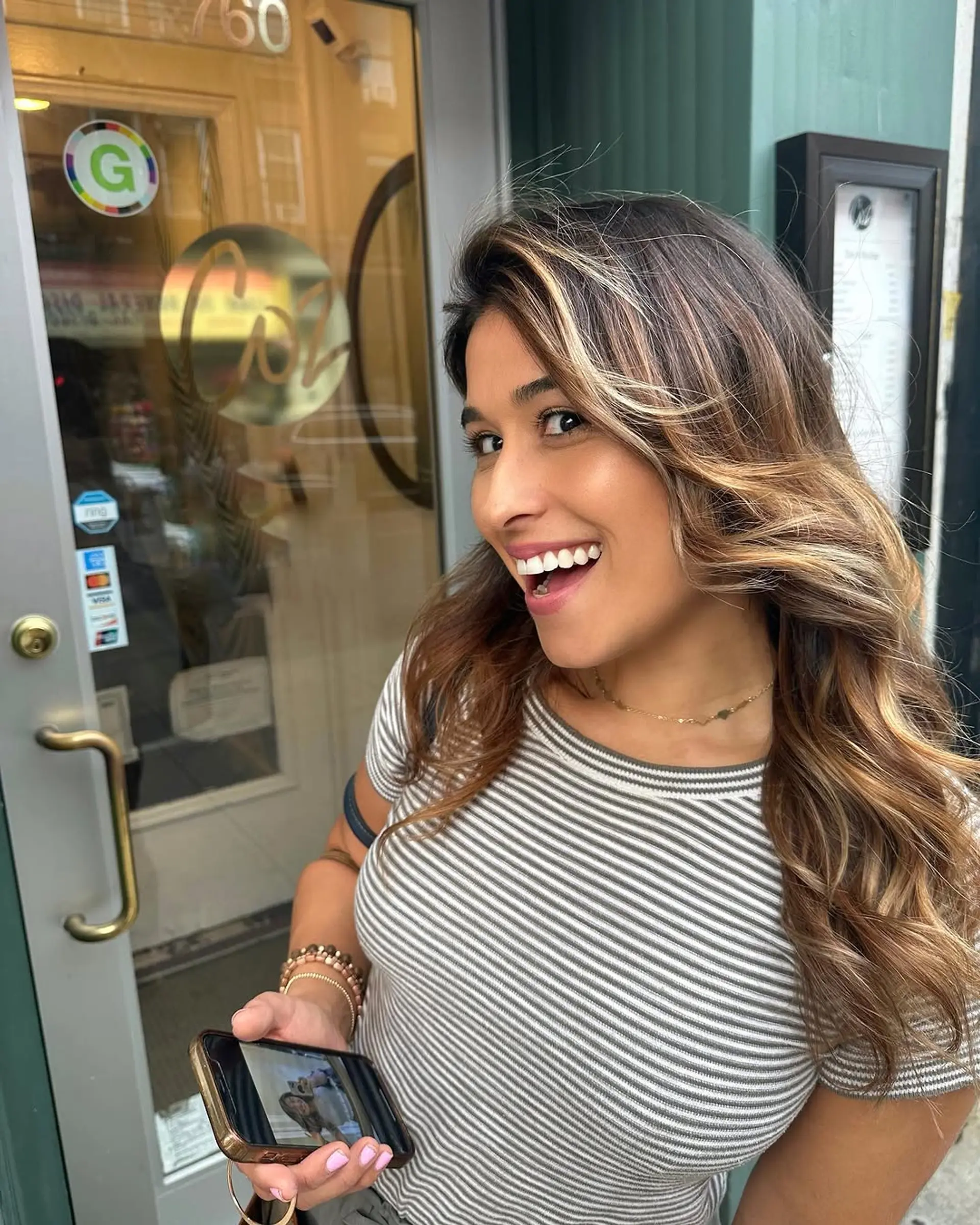 Long, cascading wavy hair with rich brown and sun-kissed blonde highlights, featuring voluminous, natural waves and a balayage technique. 3