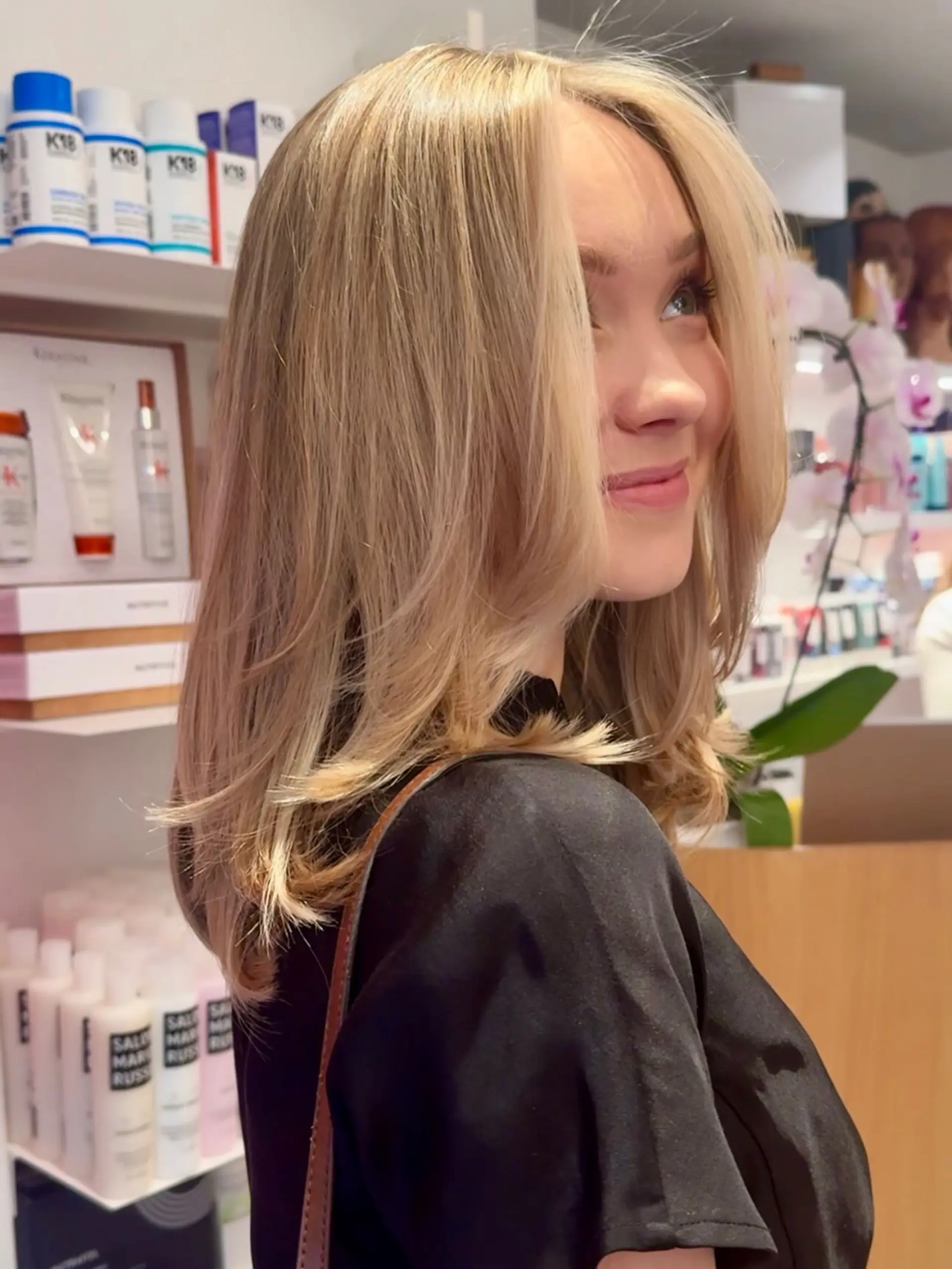 Medium-length warm blonde hair cut in face-framing layers and styled with a smooth, flippy blowout. 1
