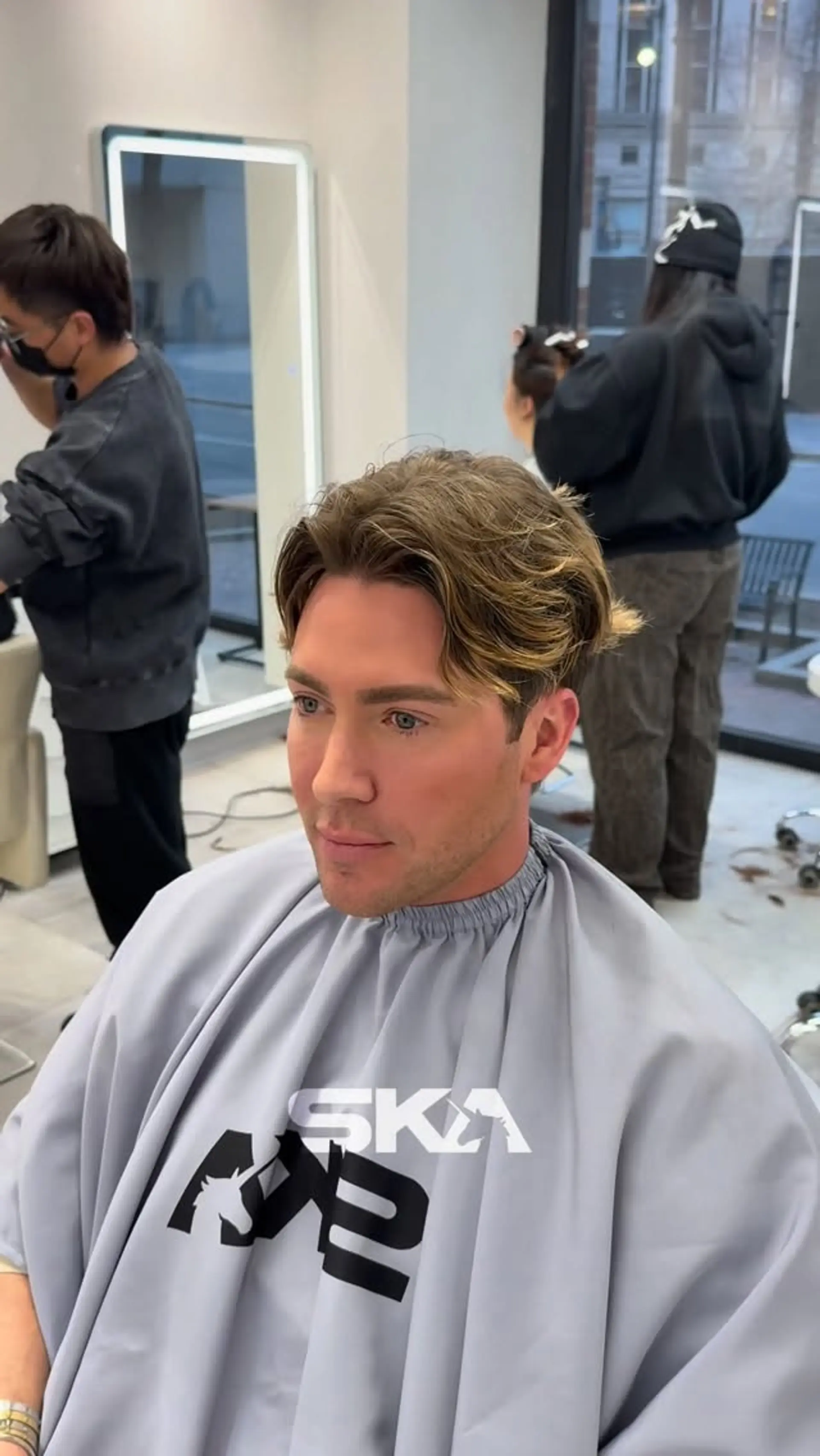 A men's short textured cut styled into a soft wavy middle part with face-framing curtain bangs. 1