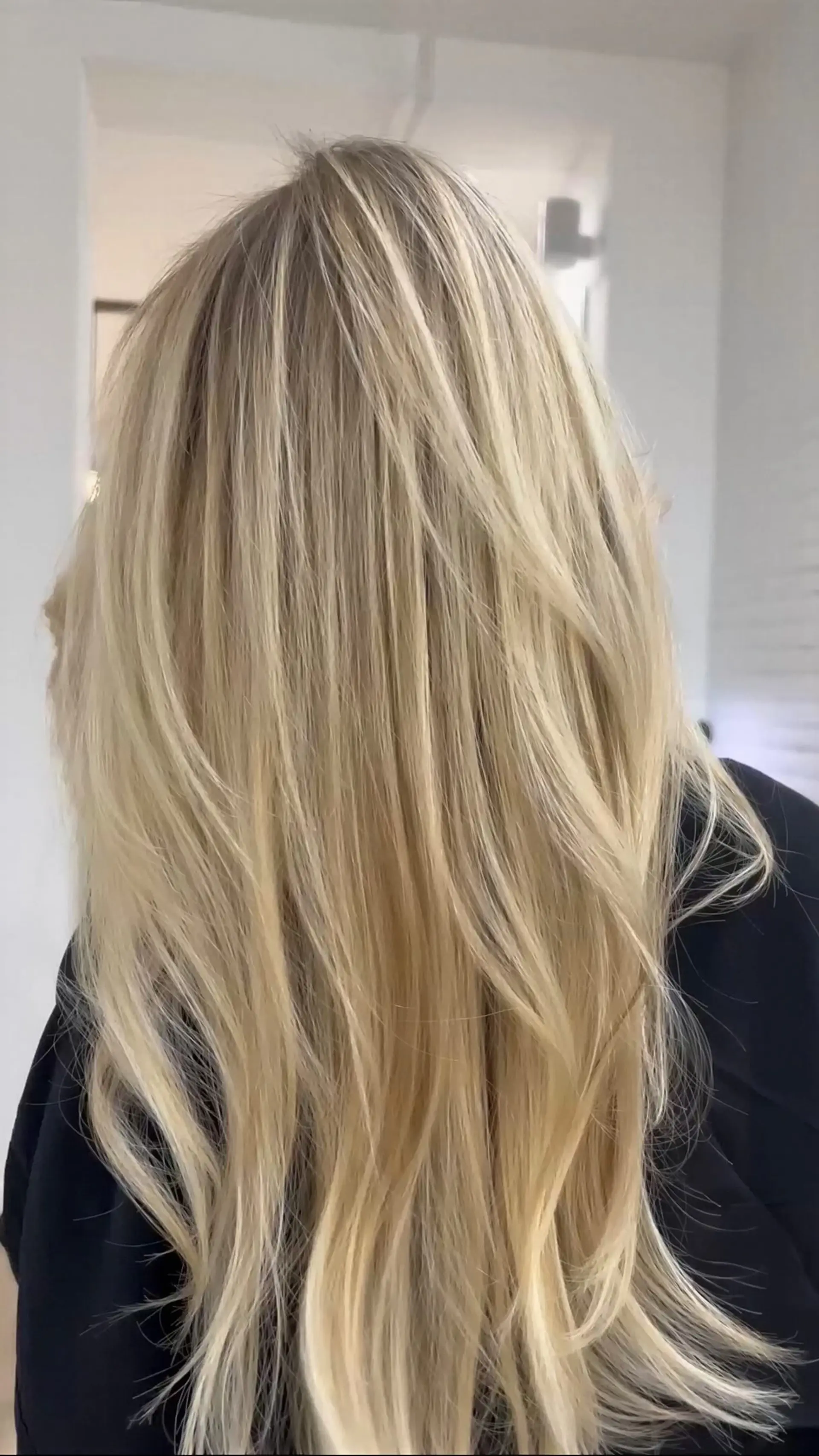 Long, bright blonde hair styled with face-framing feathered layers and a smooth, voluminous blowout. 1