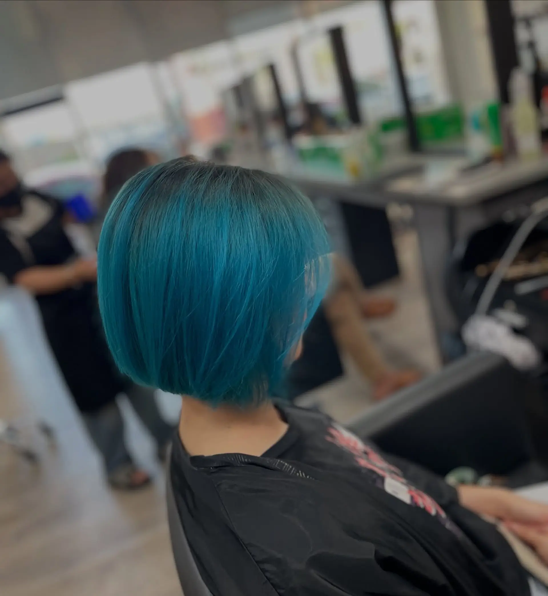 A short, straight A-line bob haircut dyed a vibrant teal color. 1