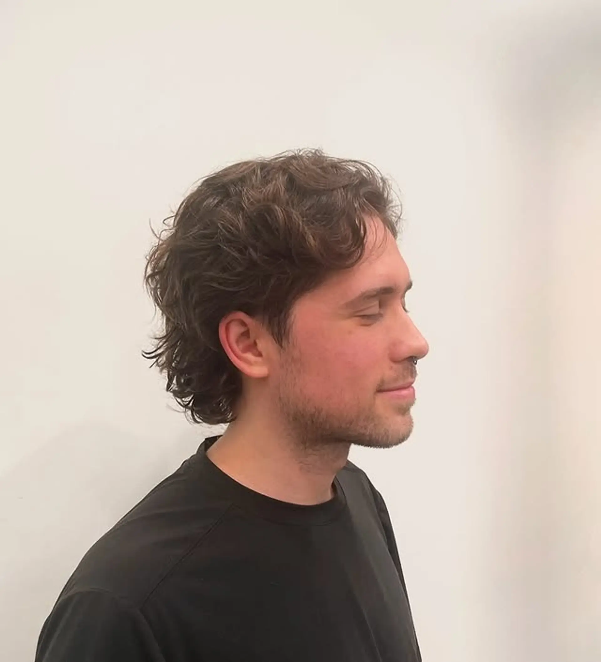 This is a modern wavy mullet with shorter layers on top and longer hair in the back, a textured, retro look. 1