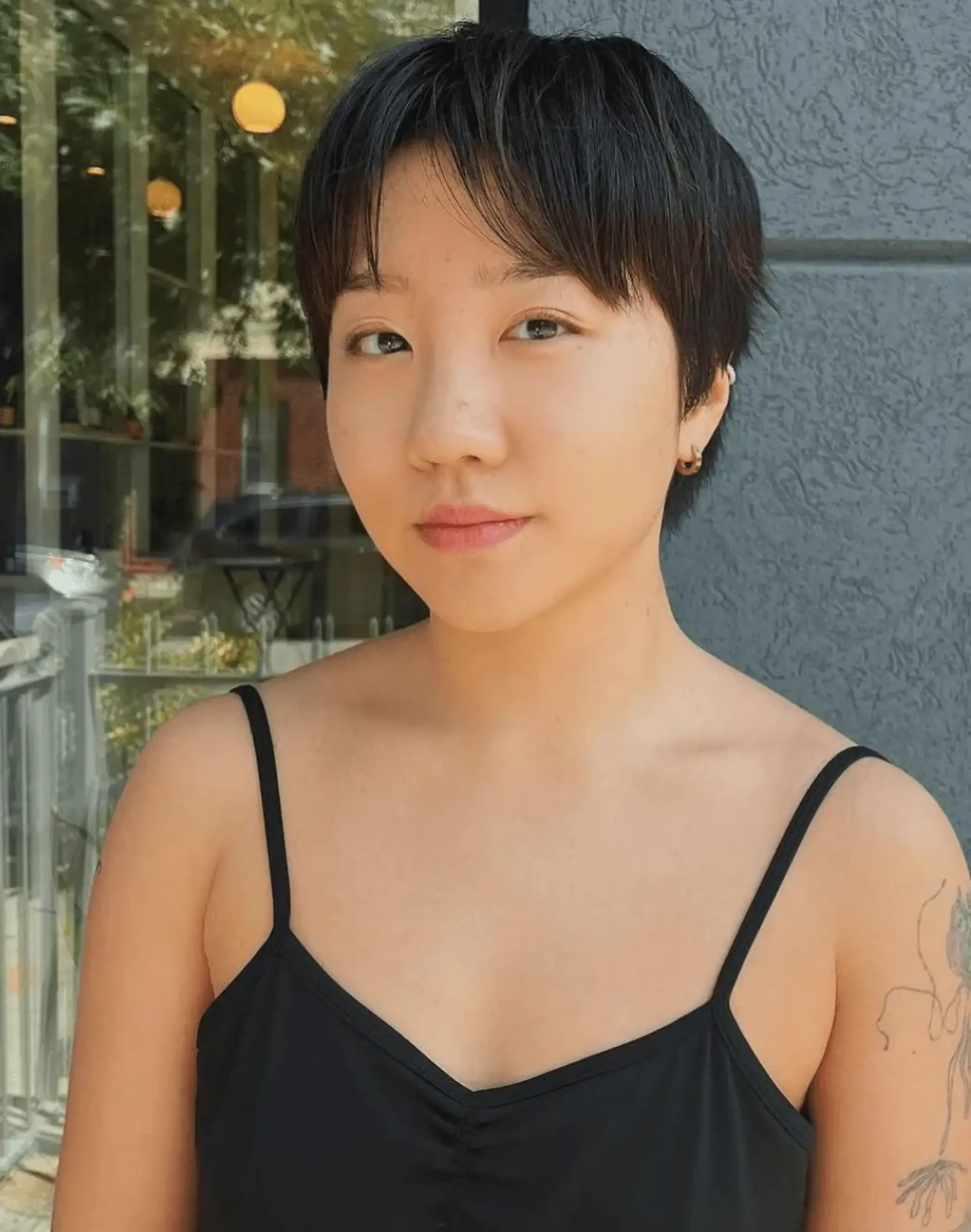 A chic pixie haircut with sleek, straight black hair cut short, featuring a short fringe. 1