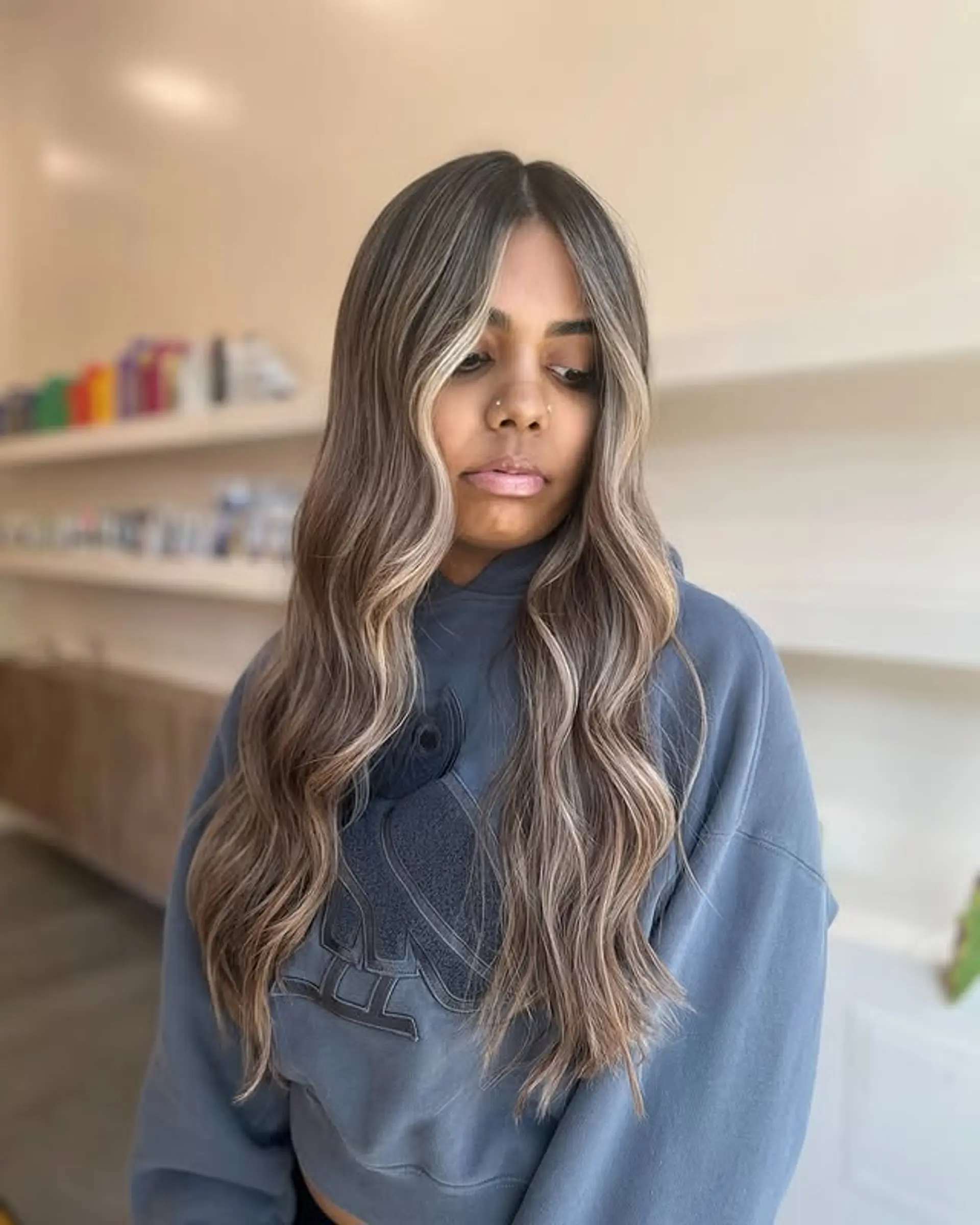 A long, wavy hairstyle with a brown base and blonde balayage, featuring a bold money piece for face-framing. 1