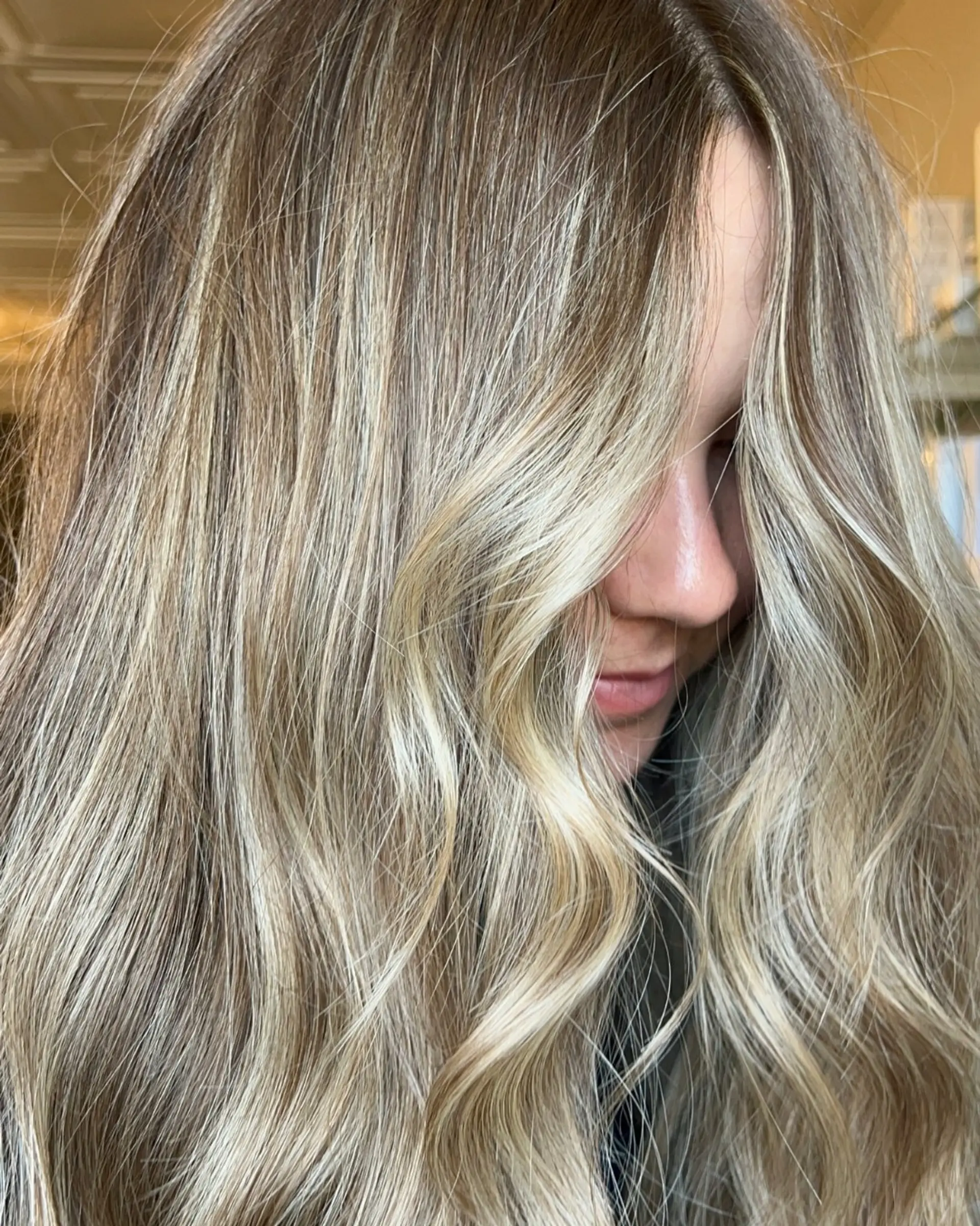 Long dimensional blonde hair styled in soft, beachy waves that frame the face. 1