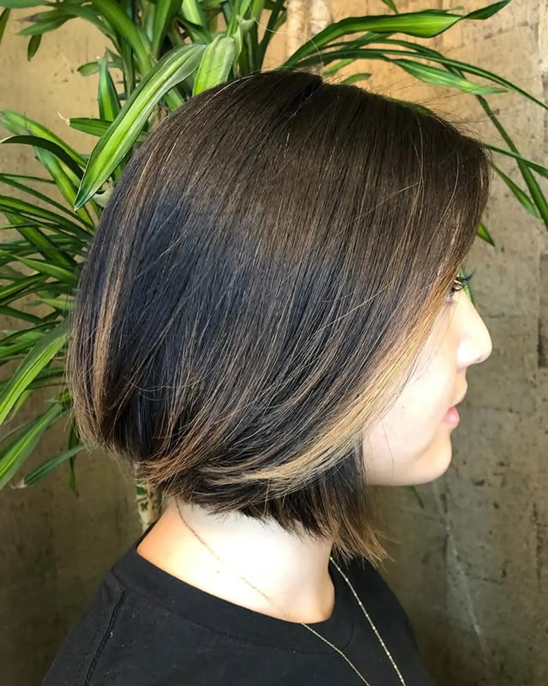 An inverted bob haircut, shorter in the back and longer in the front, with added highlights for dimension. 1