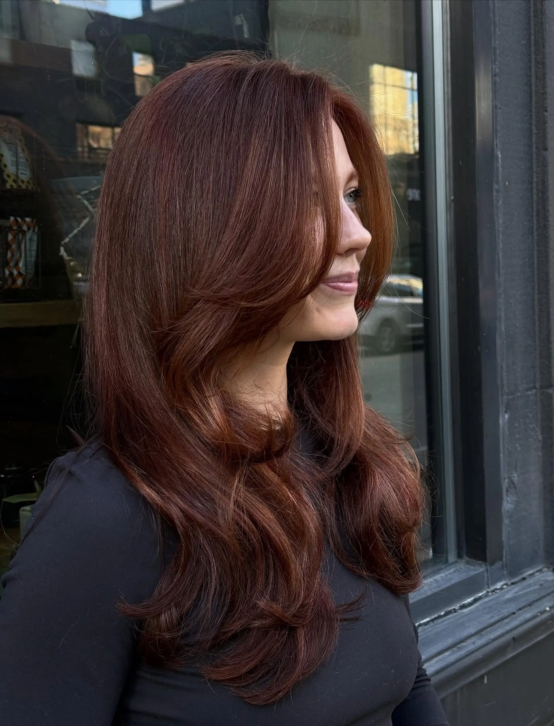 Rich, vibrant copper-auburn hair cut in soft flowing layers with face-framing pieces and styled in a bouncy, polished blowout. 1