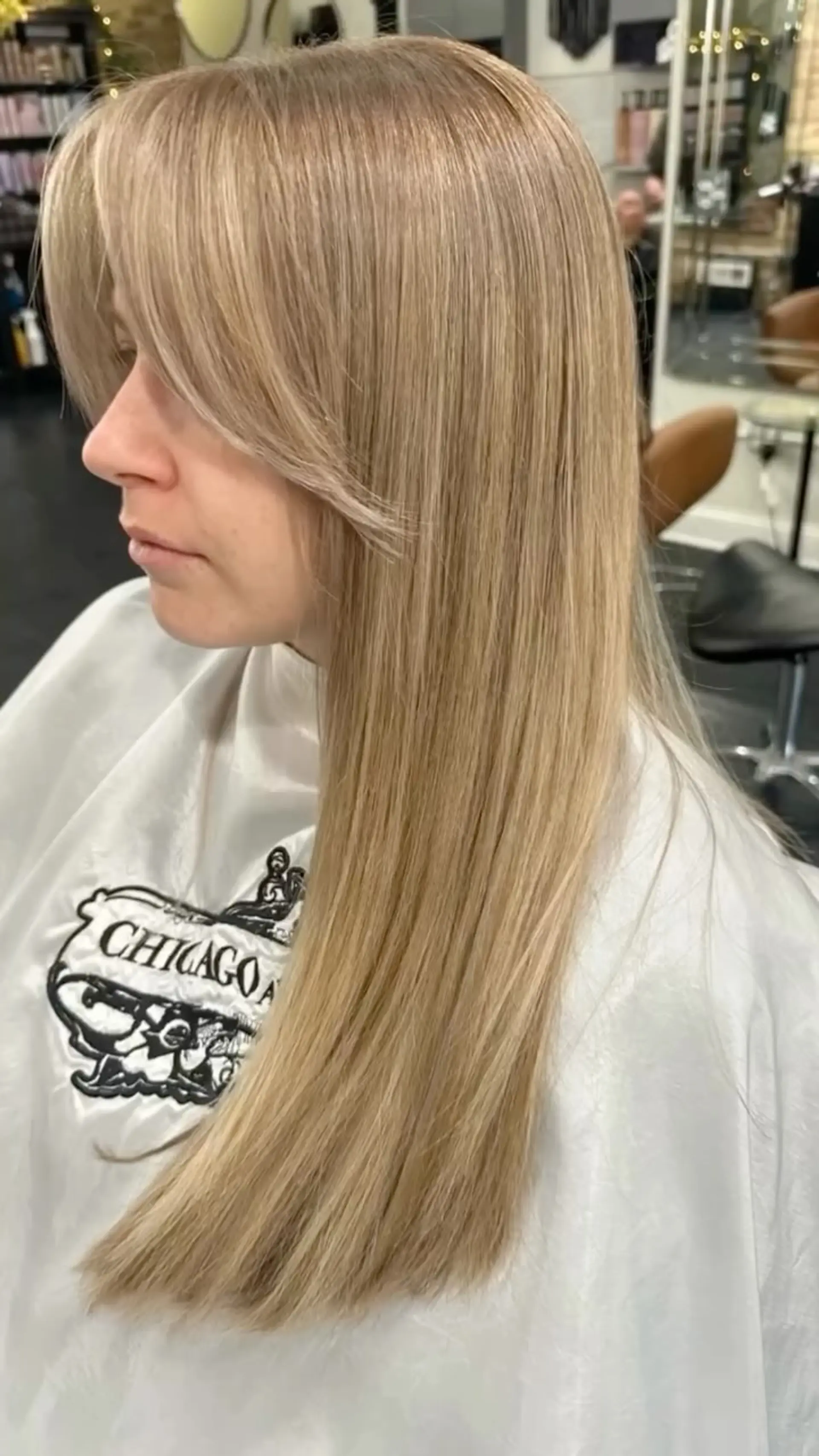 Long, silky straight blonde hair paired with soft, parted curtain bangs that frame the face. 1