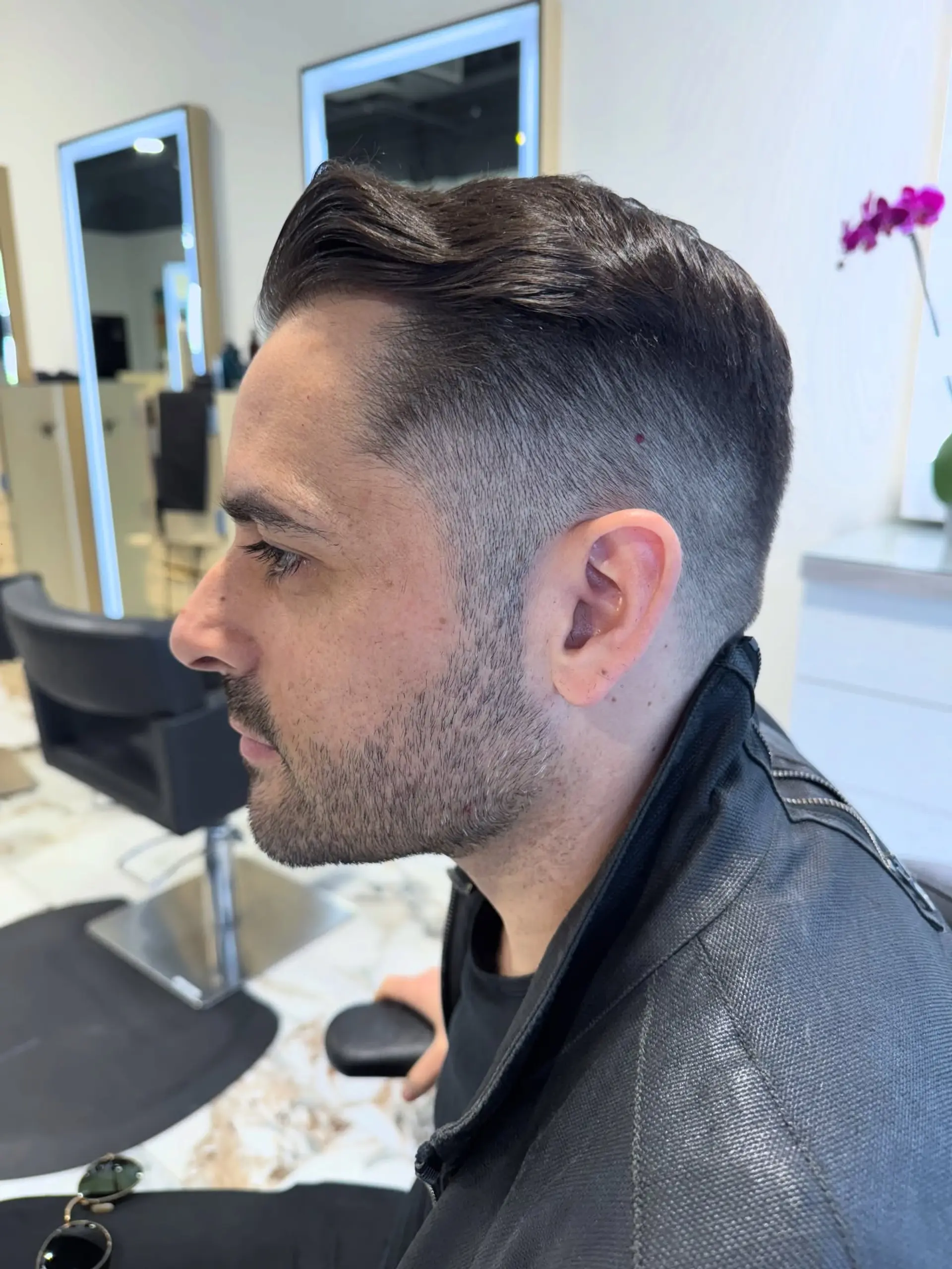 A sharp men's haircut featuring a clean fade on the sides and a longer, neatly styled top swept back. 1