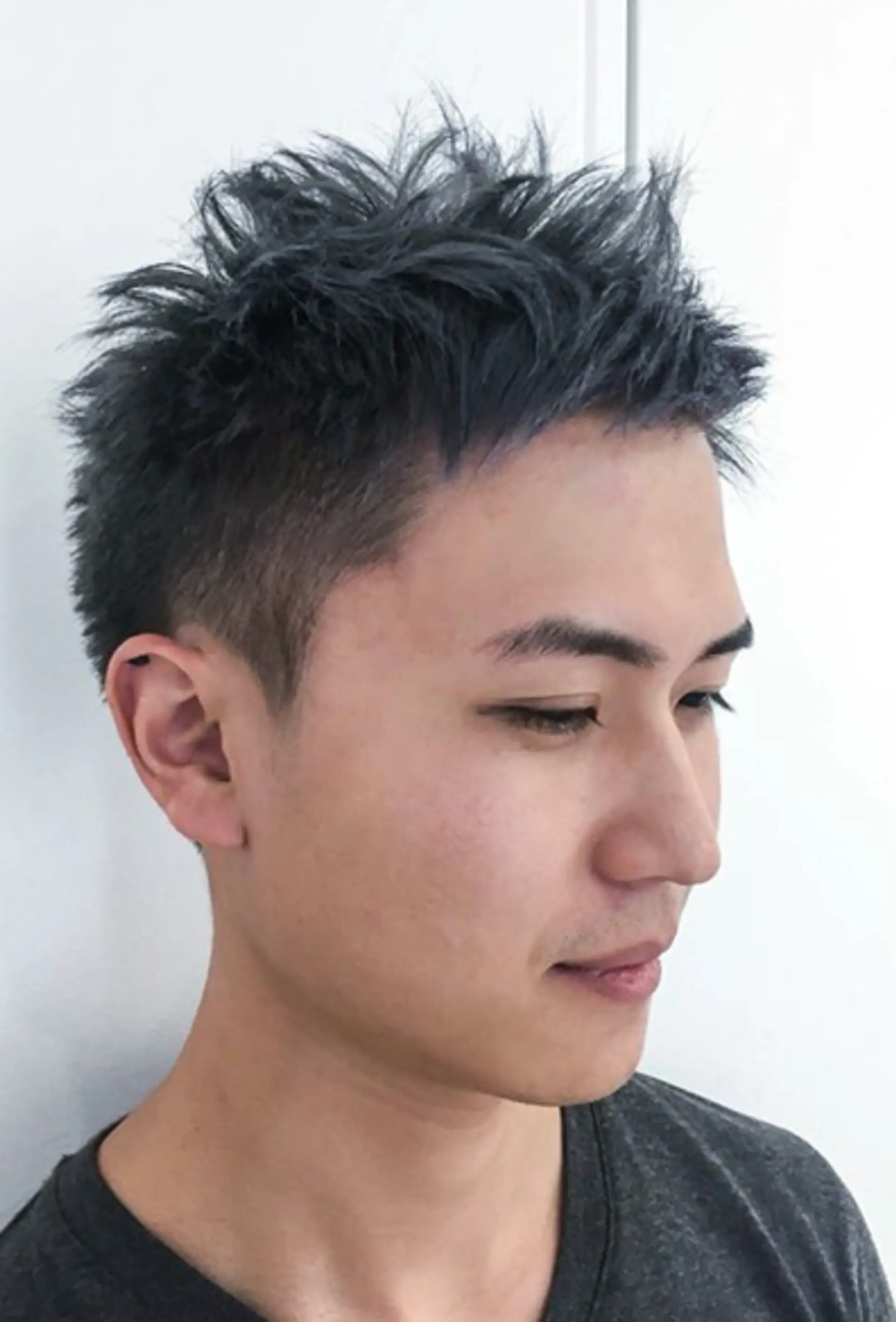 This hairstyle showcases spiky and textured layers with a predominantly blue color blended with black undertones. The sides are undercut, providing a clean and sharp contrast to the textured and spiky top, giving a modern and edgy appearance. 1