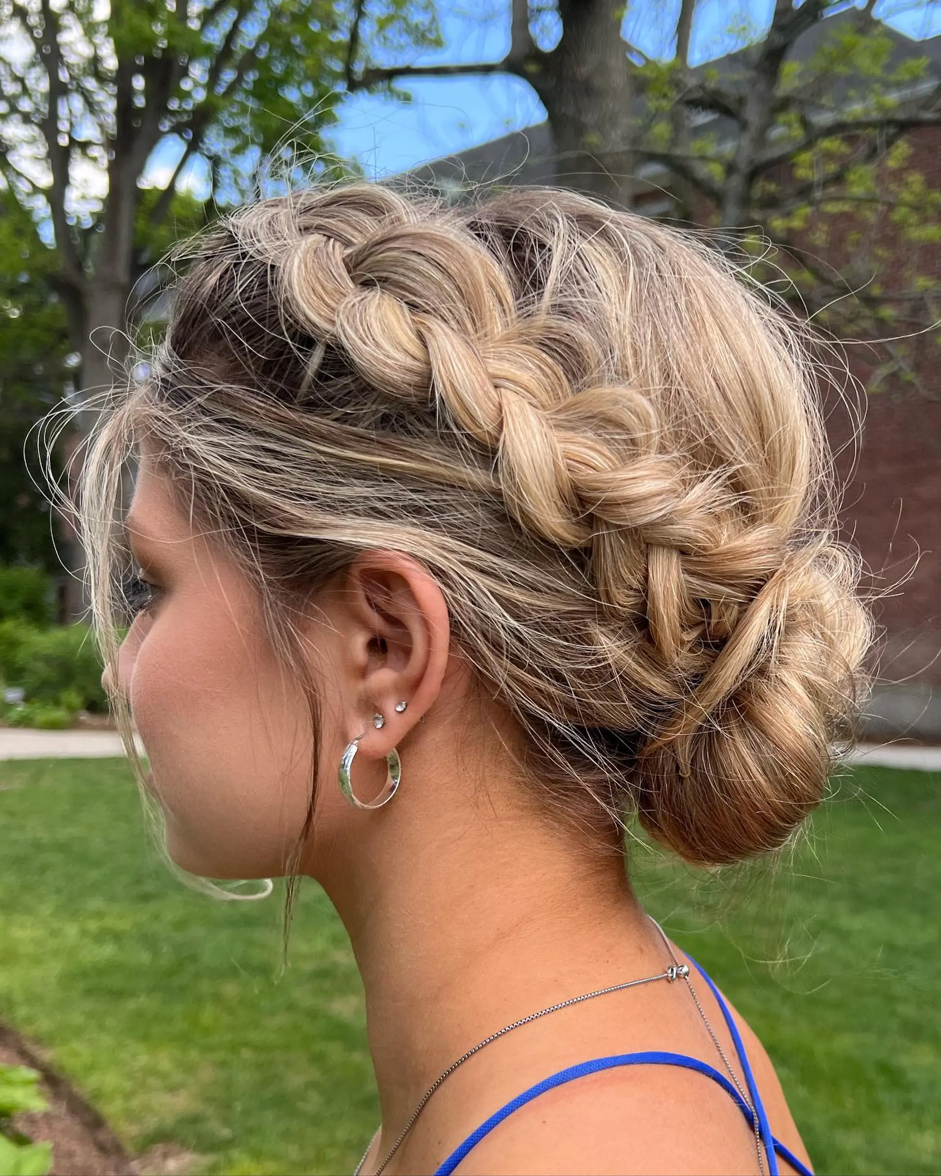 A romantic bohemian updo featuring a chunky Dutch side braid that wraps into a textured low chignon bun. 1