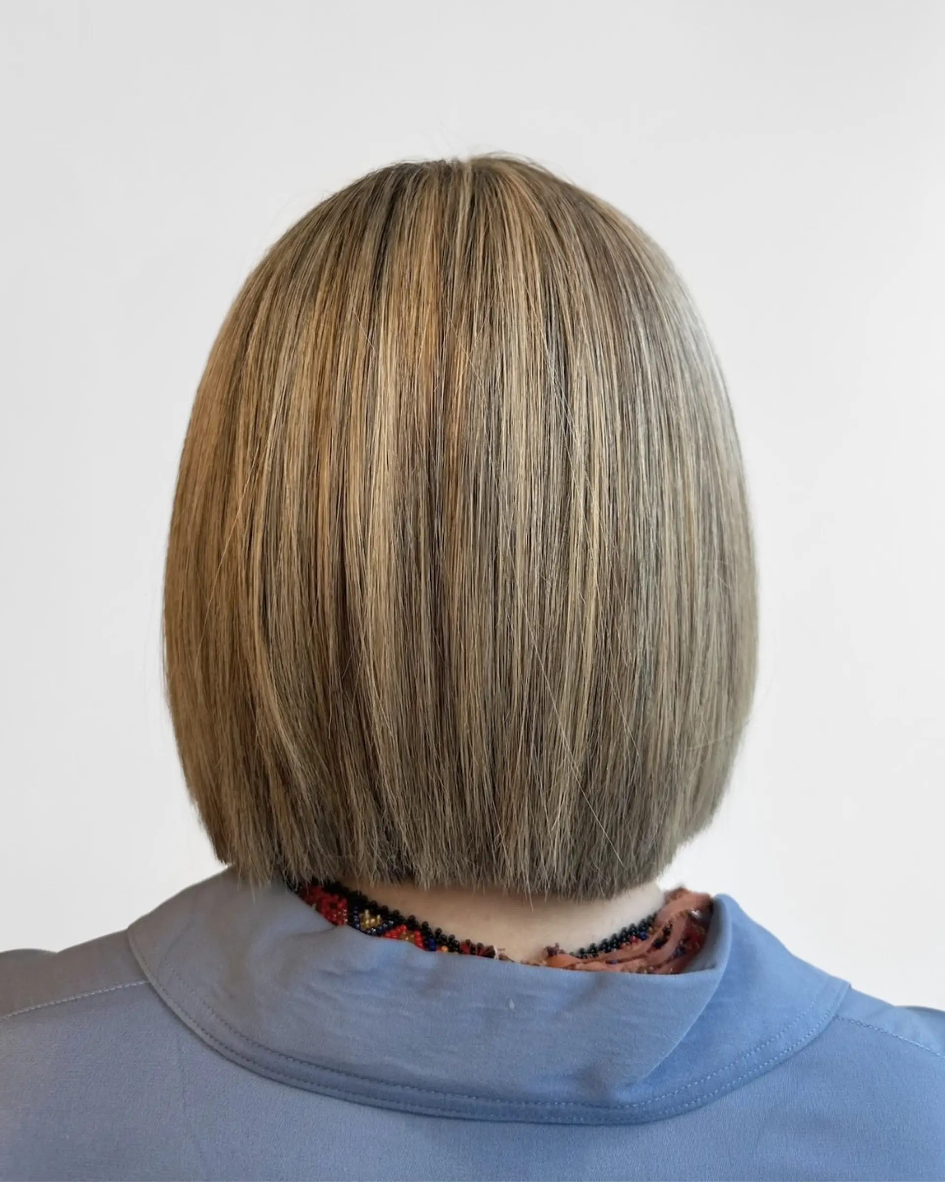 A sleek, straight short blunt bob haircut with dimensional blonde highlights and a smooth, shiny finish. 1