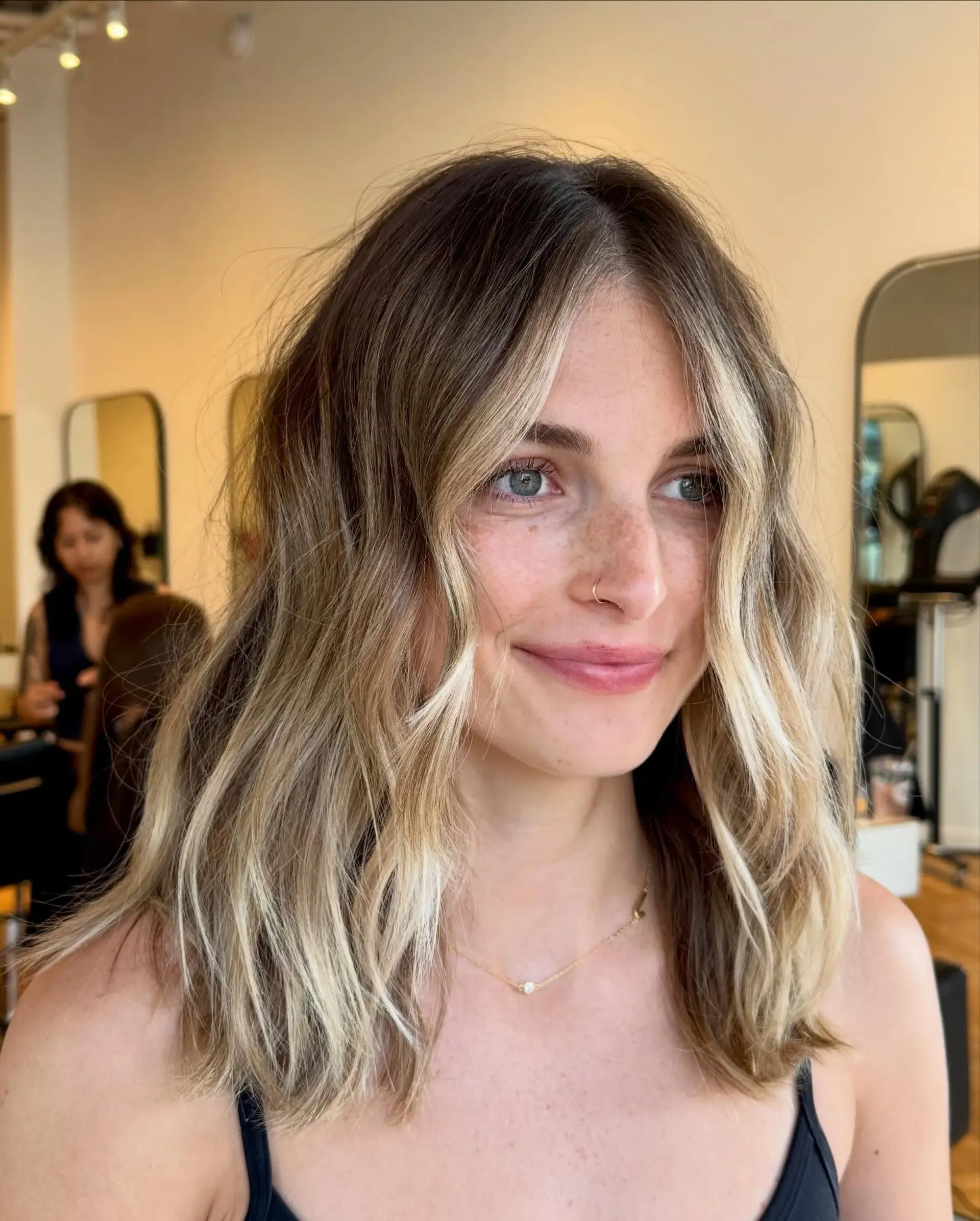 A shoulder-length wavy lob featuring bright blonde face-framing money pieces and subtle dimensional highlights. 1