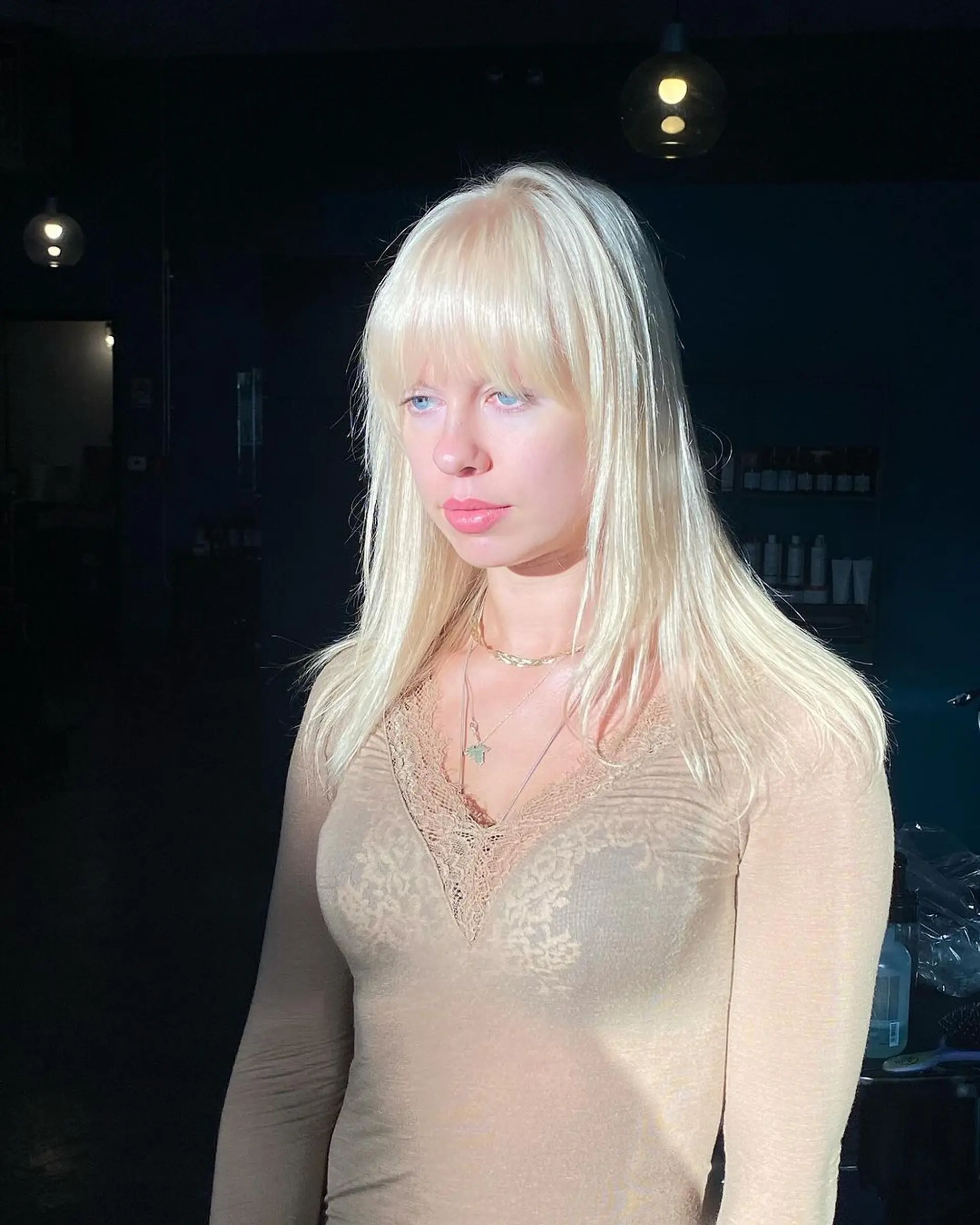 A sleek, long platinum blonde hairstyle with a full fringe. Subtle layers add dimension, while the shiny finish gives it a polished look. 1