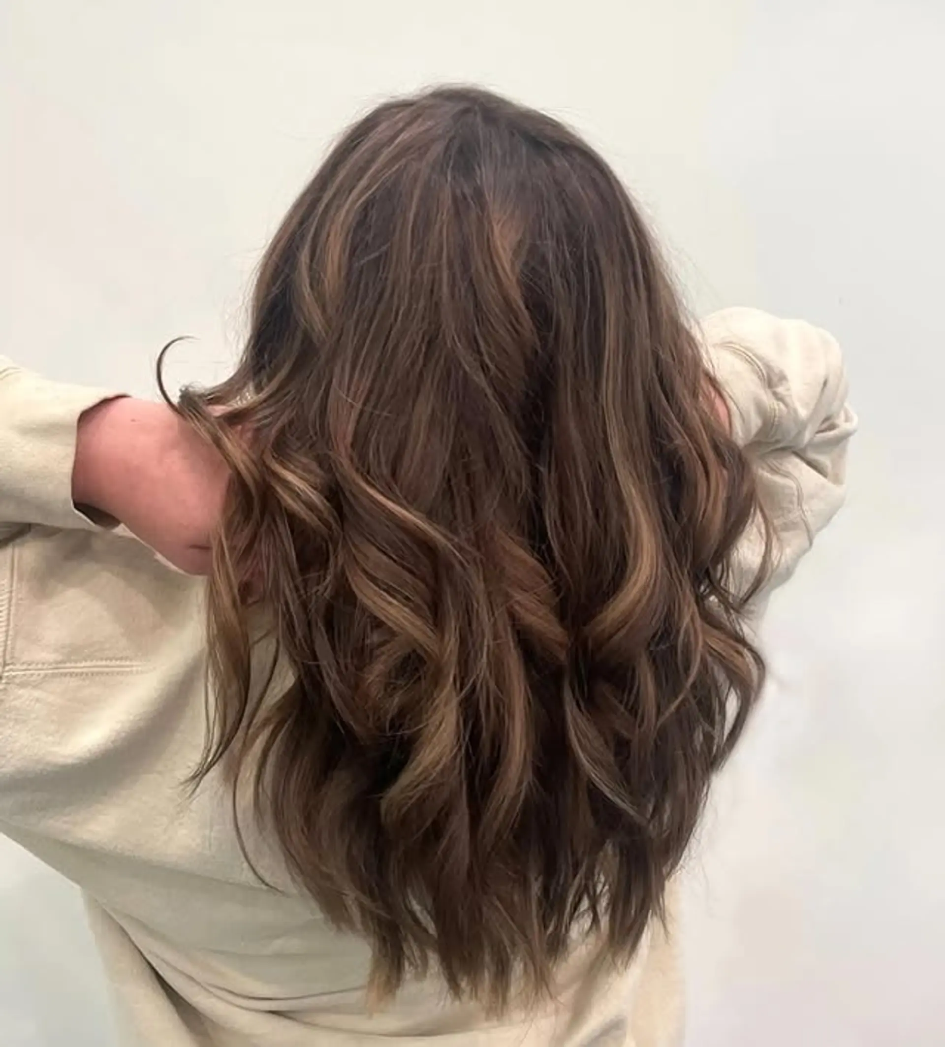 A long, layered, wavy hairstyle with a seamless blend of brown and blonde. 1