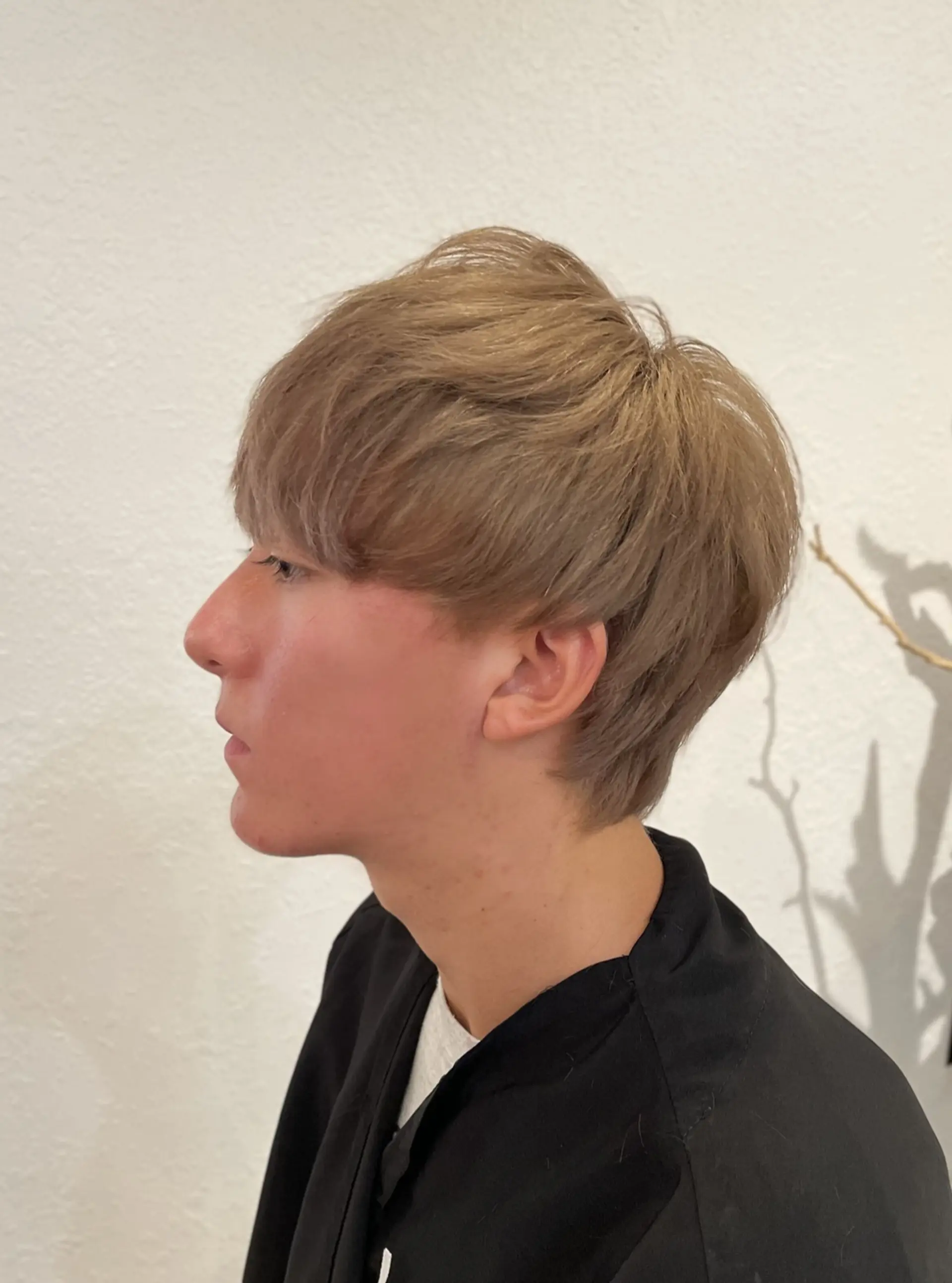 A textured short mushroom cut featuring soft forward-swept bangs and a rounded silhouette, finished in a creamy milk tea beige shade. 1