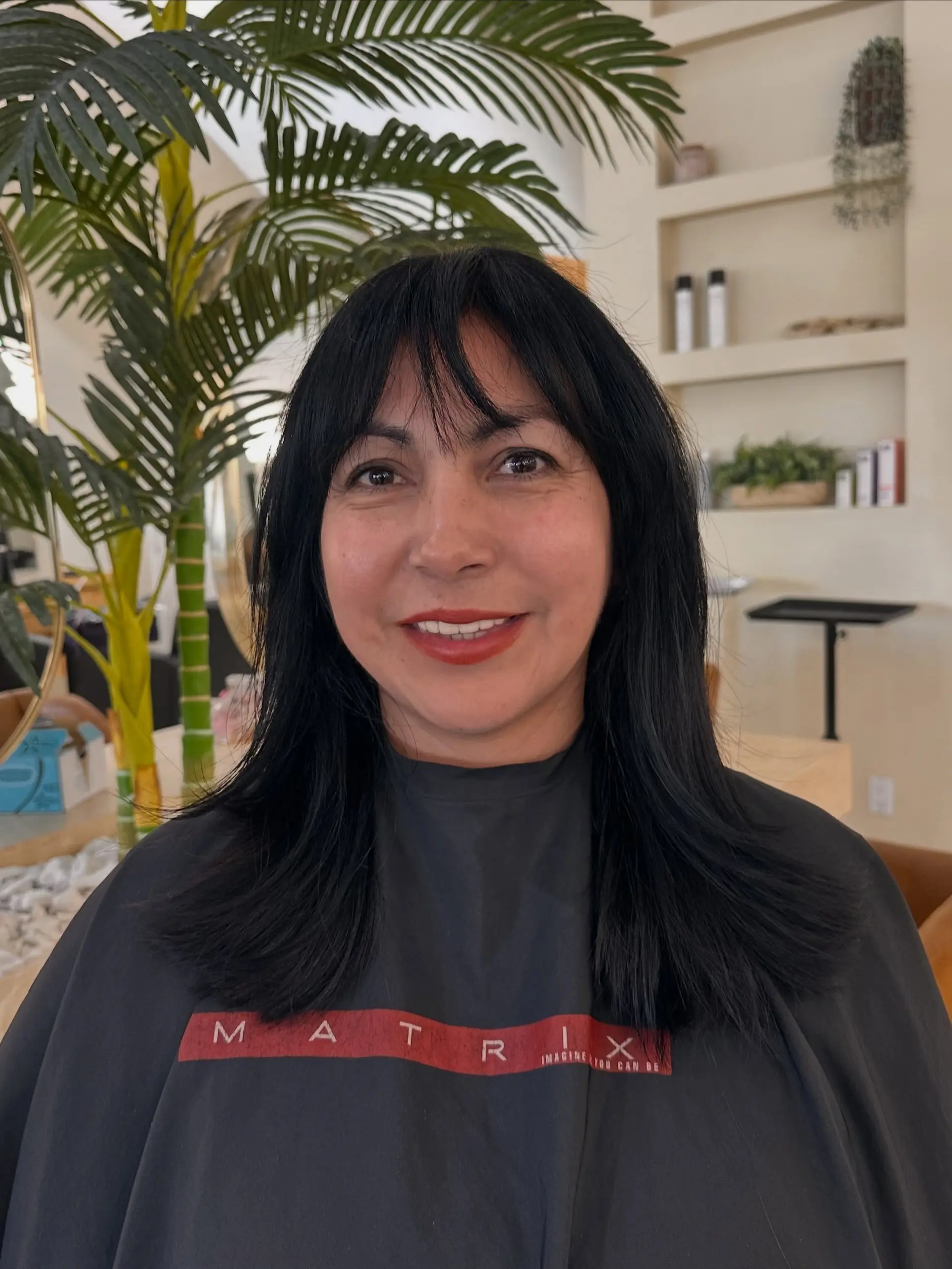 A medium-length jet black haircut featuring seamless layers and light, wispy bangs. 1
