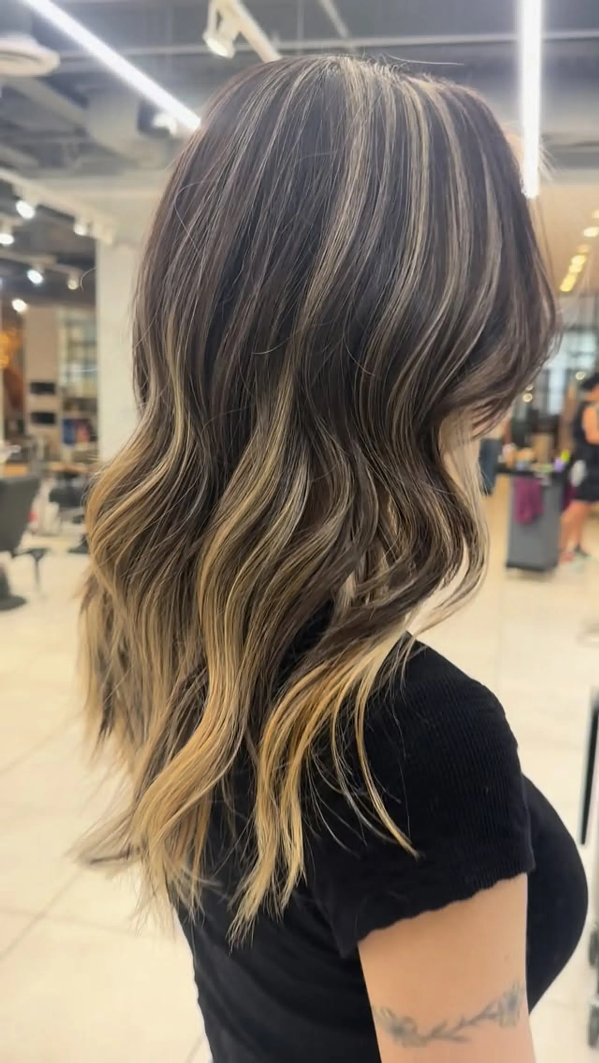 Warm honey blonde balayage highlights blended through a dark brunette base and styled in loose, soft waves. 1