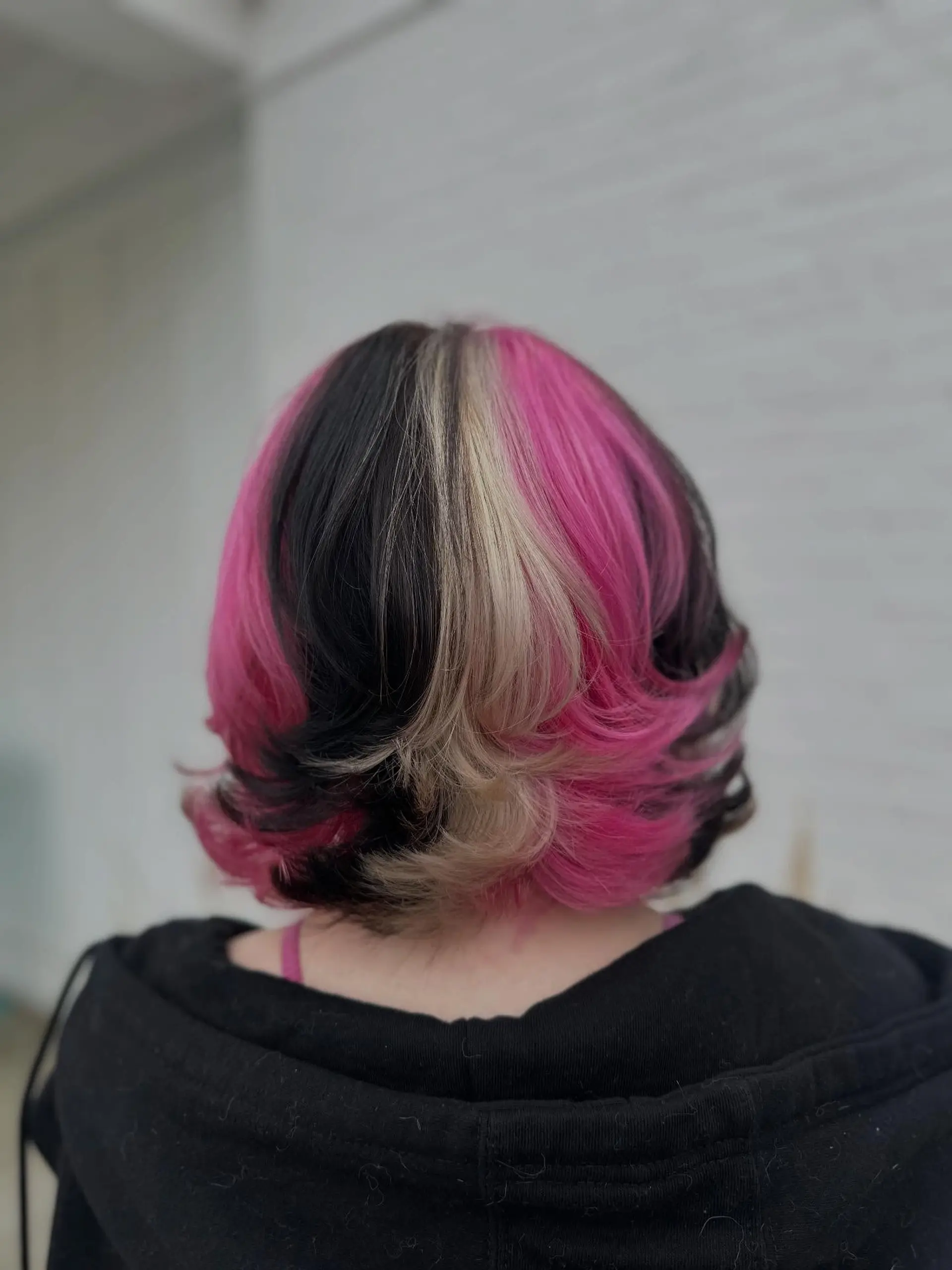 A layered, neck-length bob styled with flared ends, showcasing distinct Neapolitan block coloring in pink, blonde, and dark brunette. 1