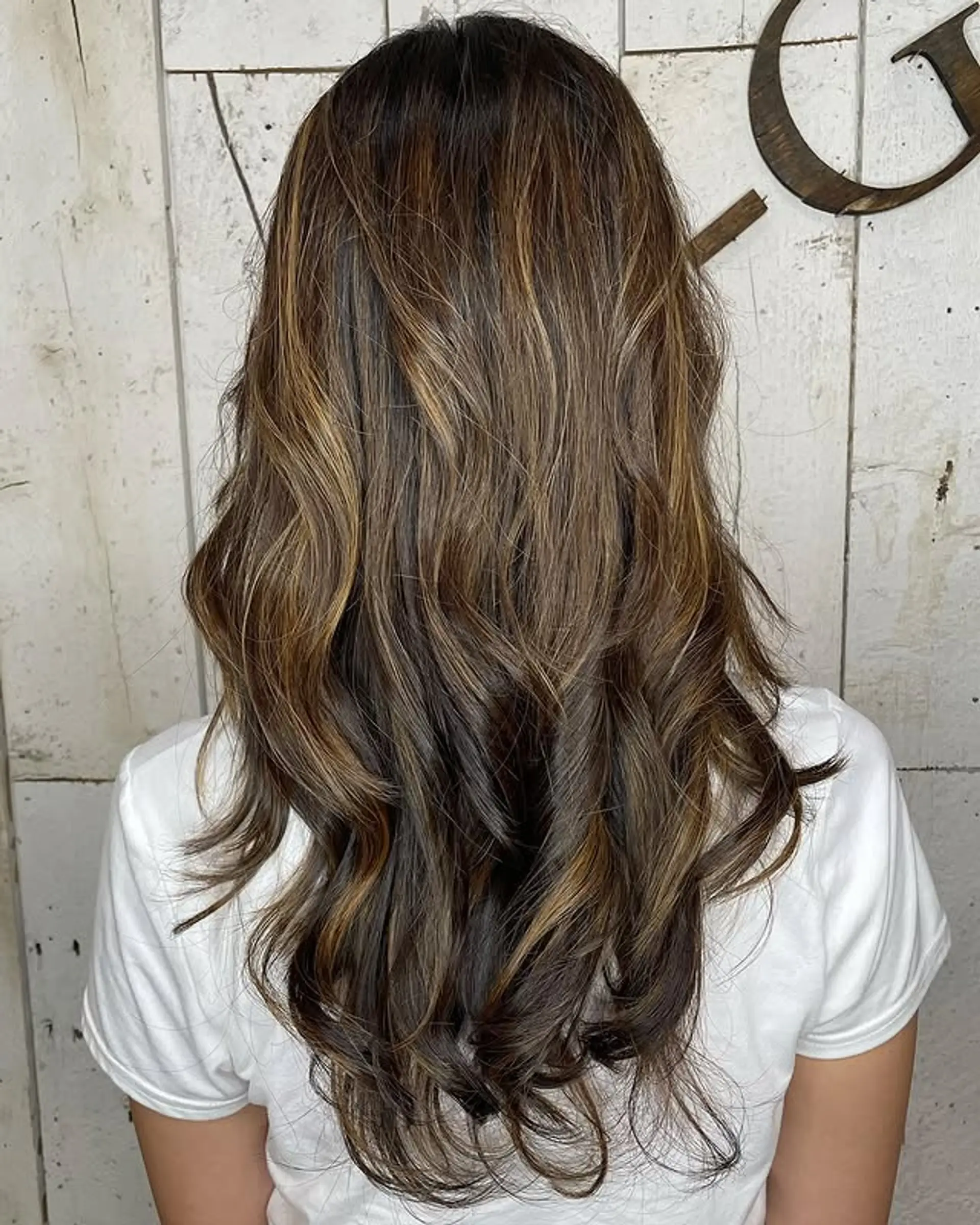 A long layered haircut with face-framing and a balayage color technique. 1