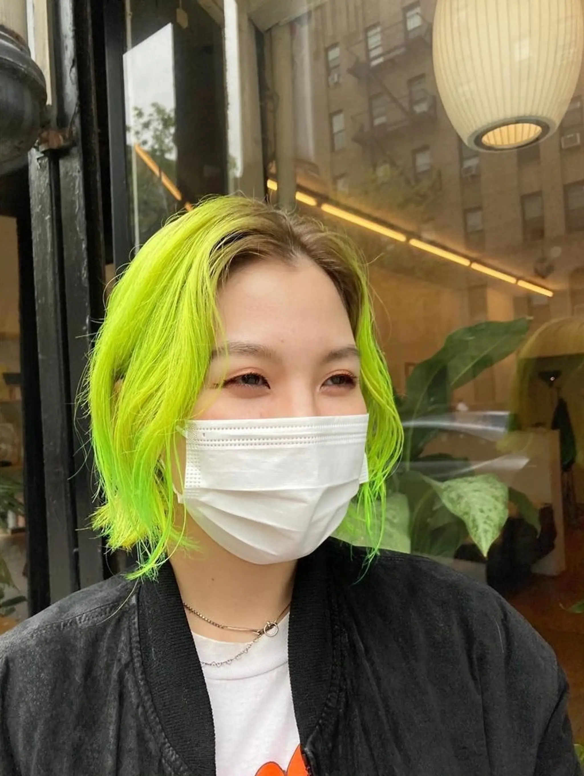 A short, straight bob with blunt cut ends, featuring a vibrant neon green color with dark roots and a middle part.