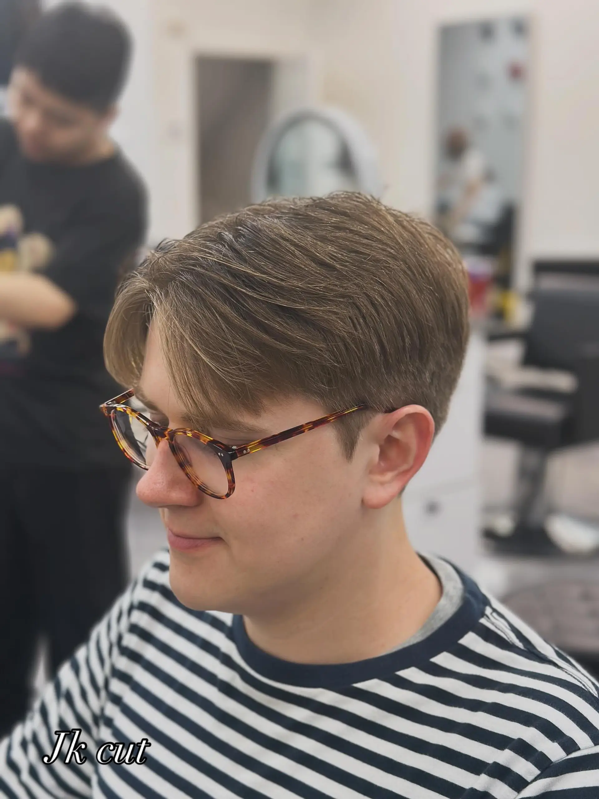 A men's short haircut featuring a parted curtain fringe with softly tapered sides and a natural finish. 1