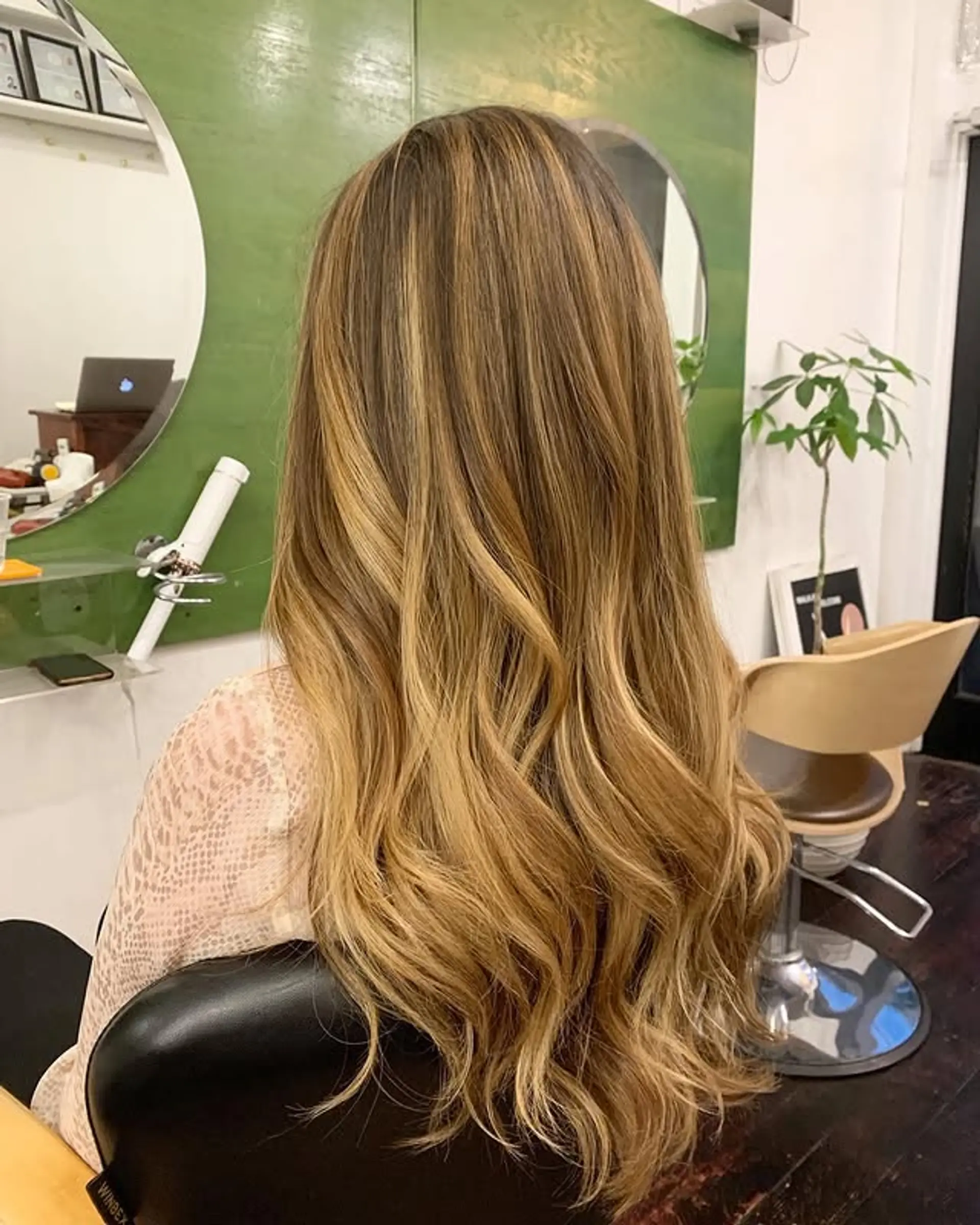 Long, wavy hair with a caramel blonde balayage, seamlessly blending dark roots into lighter ends. 1