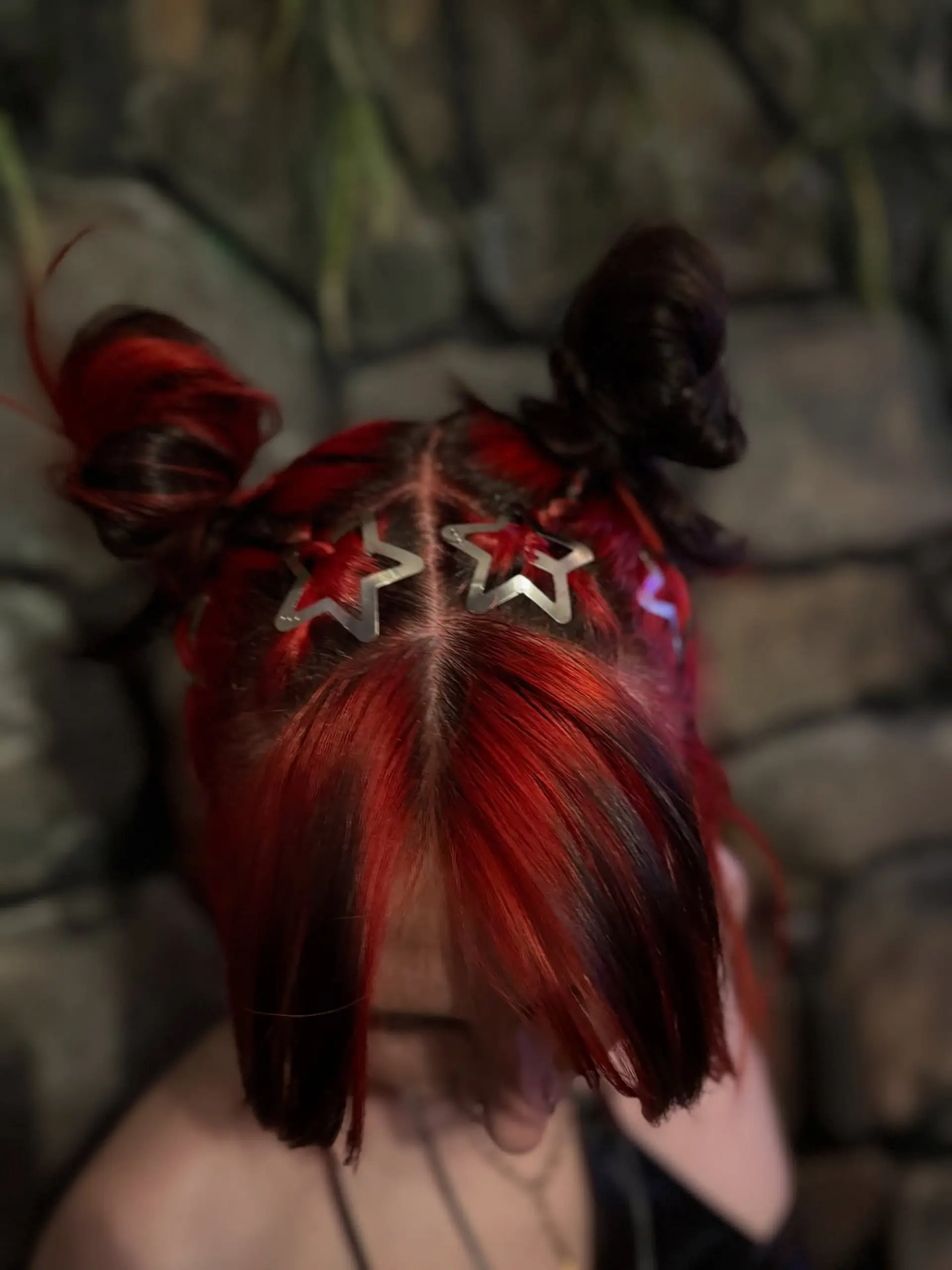 A creative updo featuring high space buns in vivid red and deep black, decorated with silver star clips. 1