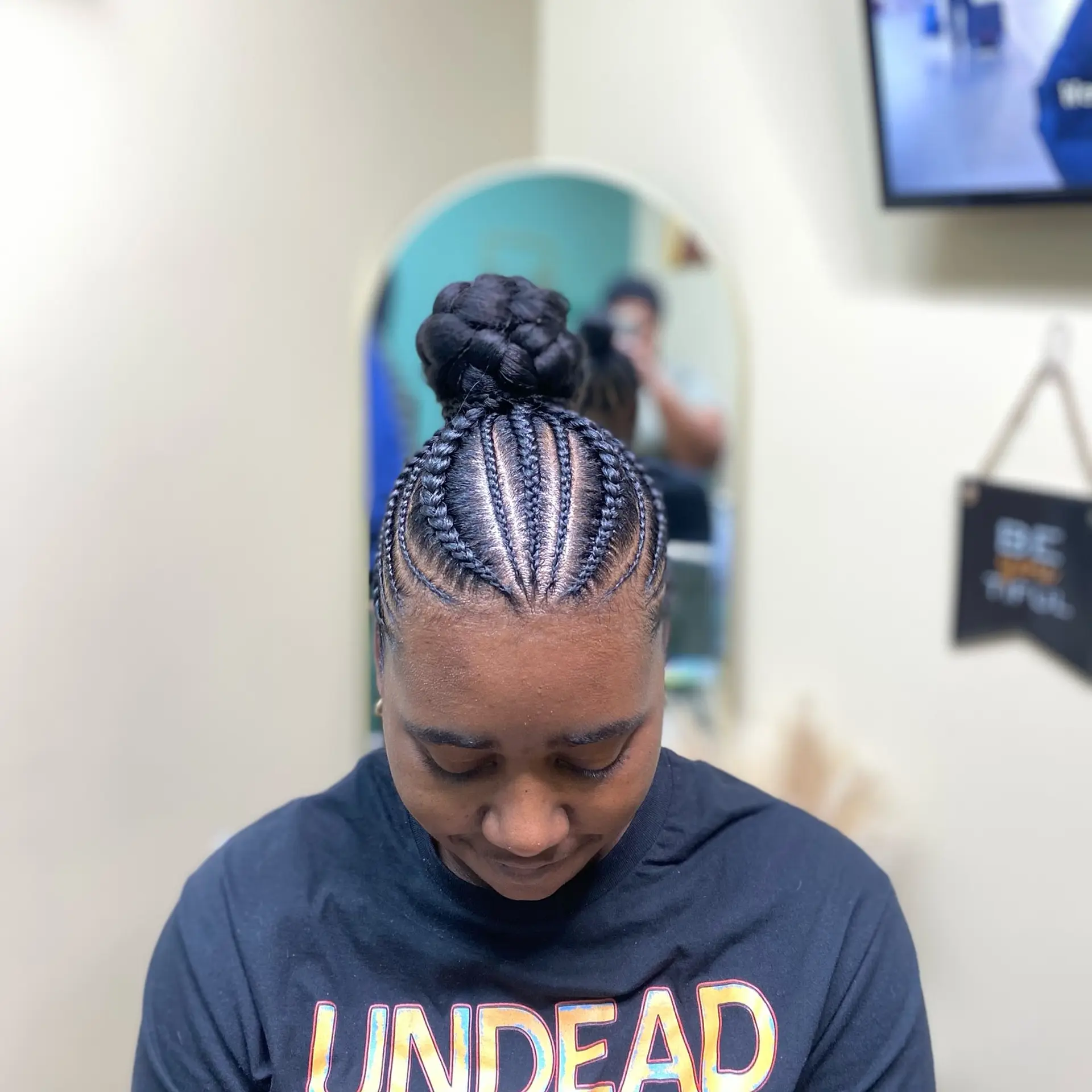 Clean, intricate cornrows braided upward from the hairline into a high braided bun. 1