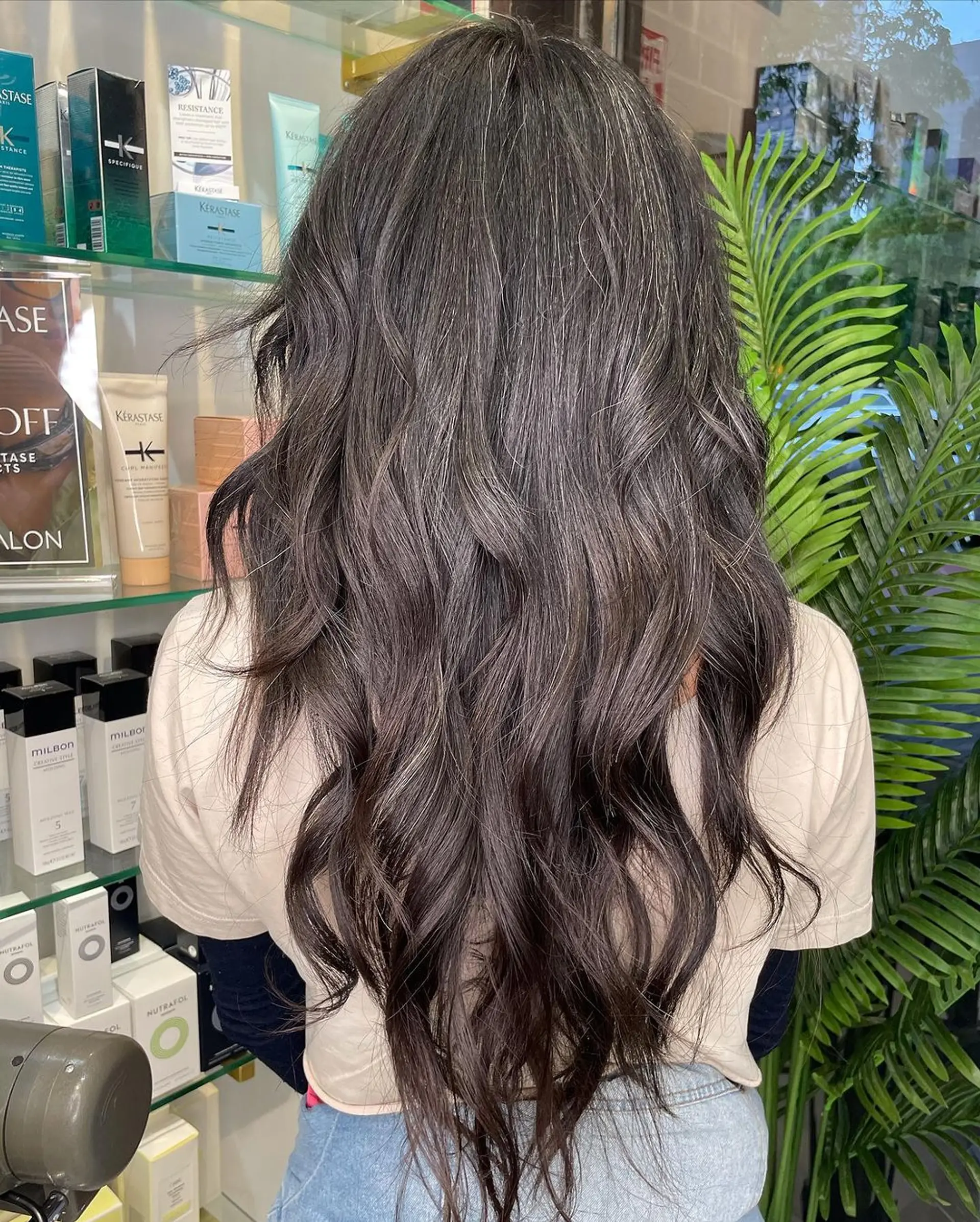 Very long, dark brown and black wavy hair with natural waves cascading down the back, creating an elegant and flowing silhouette. The hair has luminous highlights with a layered texture. 1