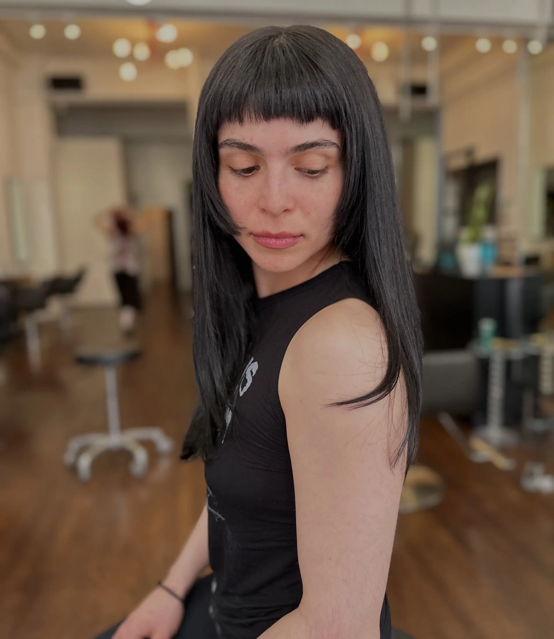 Straight jet-black long hair cut with blunt micro bangs and chin-length face-framing layers. 1