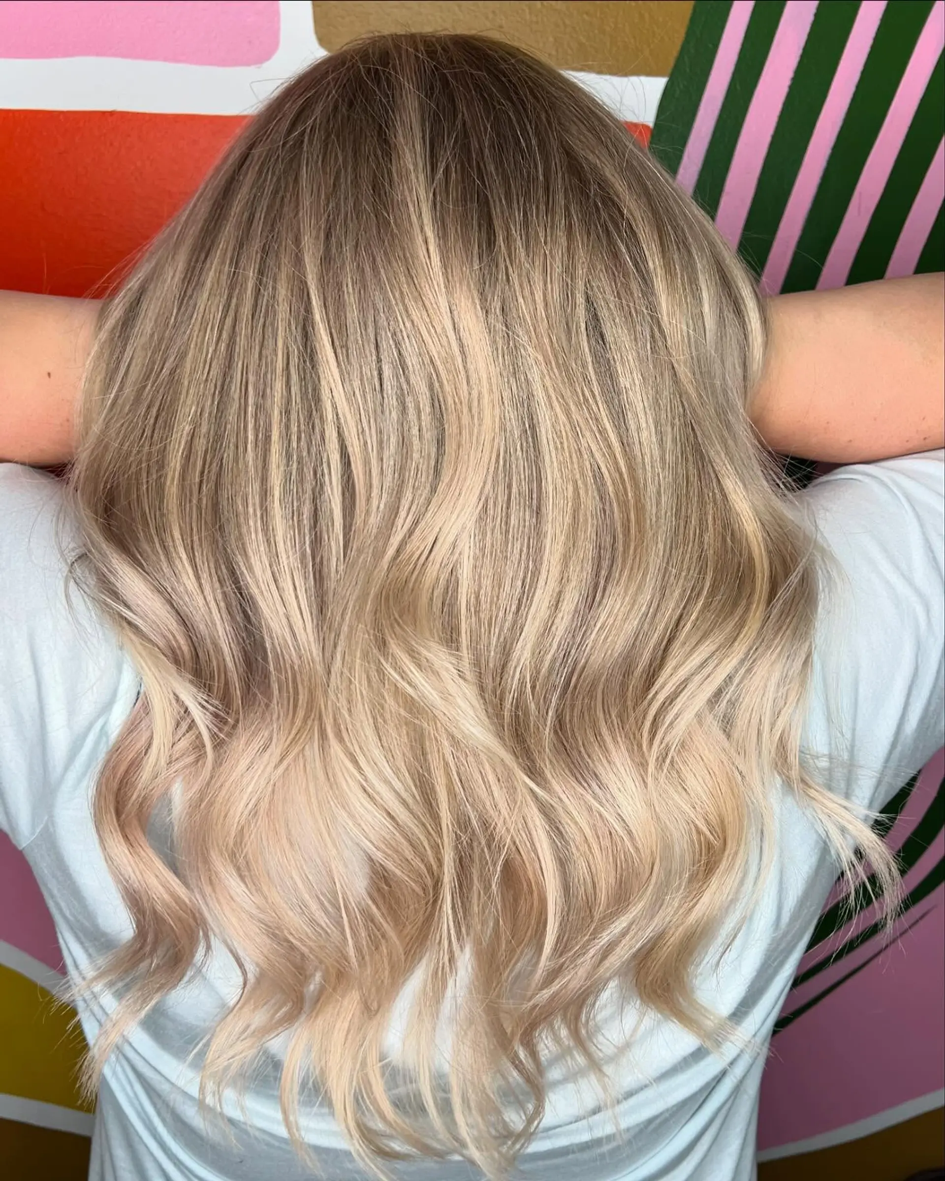 Dimensional cool-toned blonde balayage with a natural shadow root and soft, relaxed waves. 1