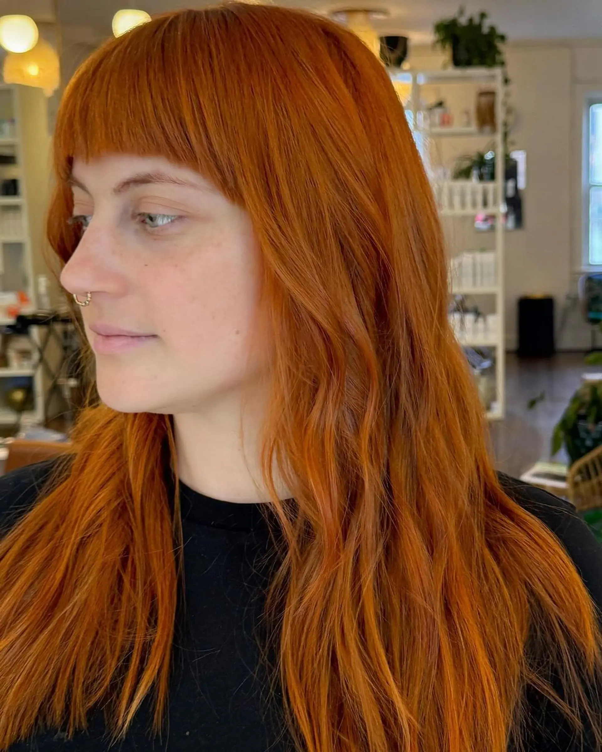 A long, wavy style with copper color featuring blunt bangs and soft, cascading waves that give a vibrant effect. 1