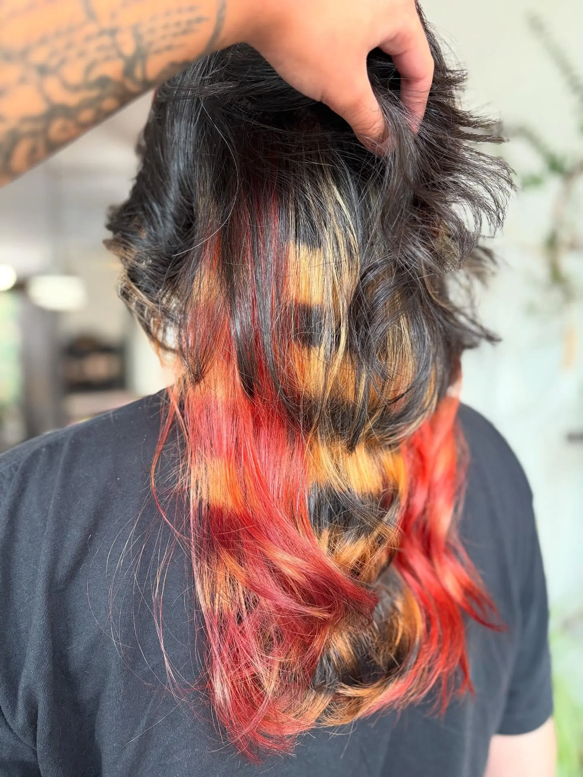 Medium-length dark hairstyle featuring alternative calico and raccoon tail banded peekaboo color in vibrant red, blonde, and black. 1