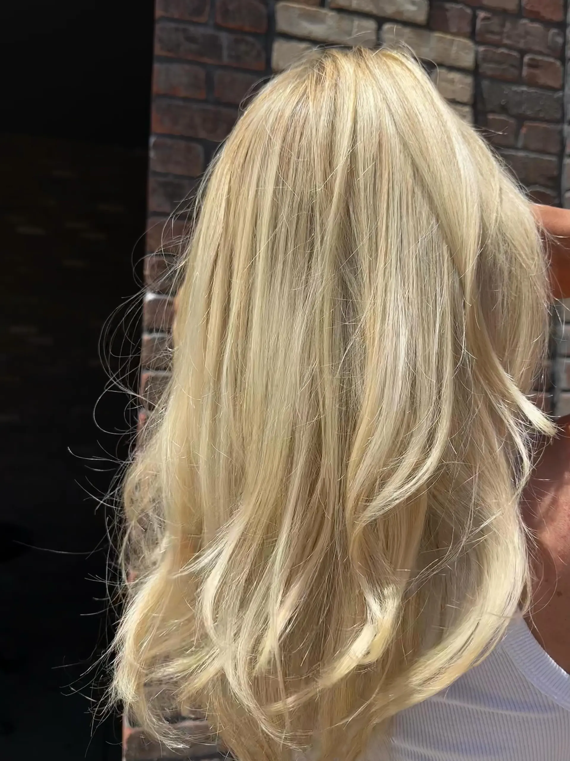 Radiant multi-tonal blonde hair cut in long layers and finished with a soft, curved blowout. 1