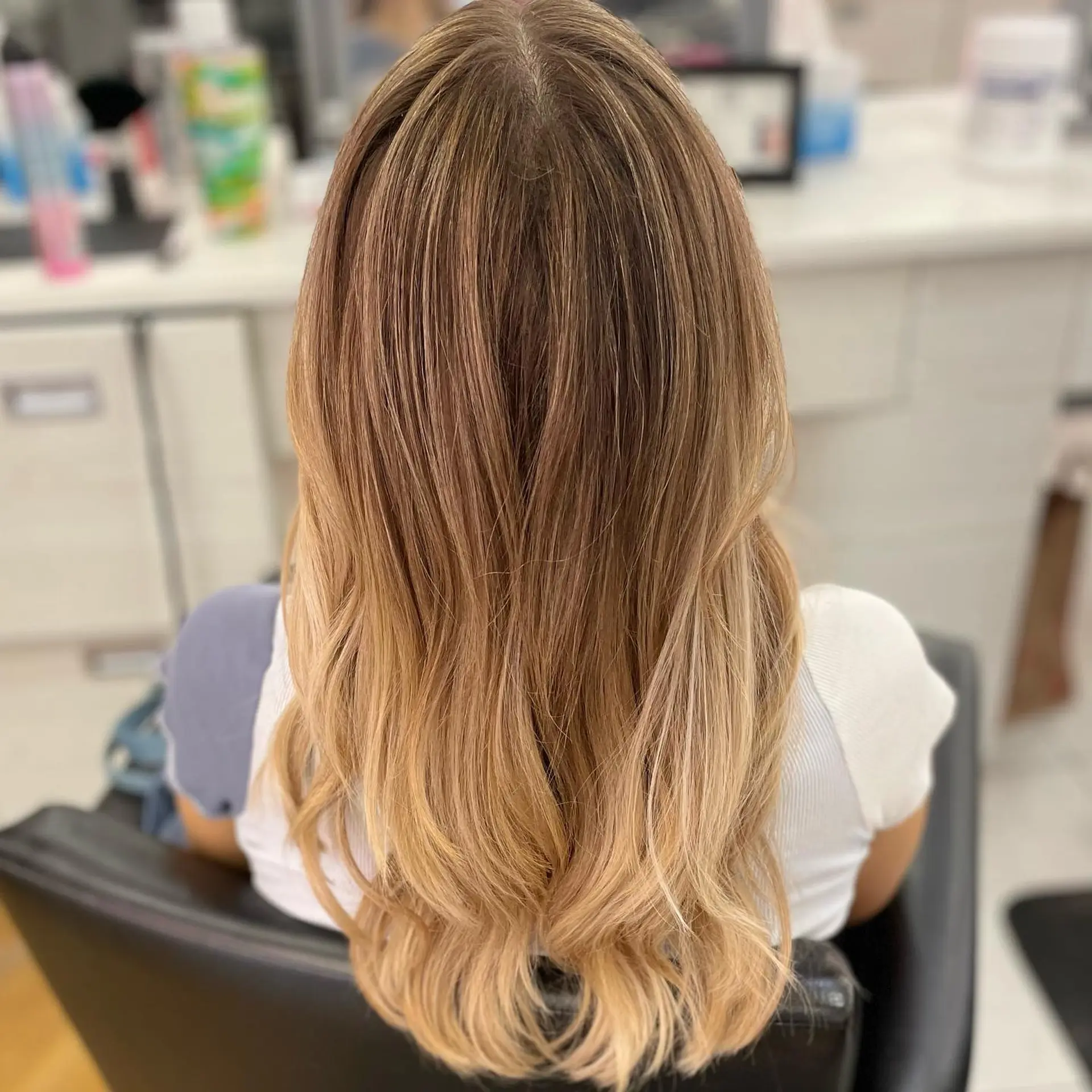 Long warm blonde hair with seamless teasylights blended from a natural base into soft, wavy ends. 1