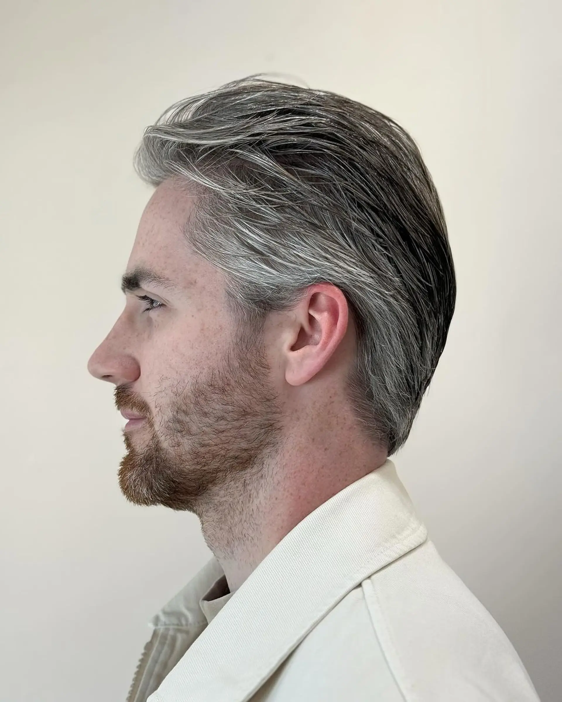 Short wavy hairstyle with a side part, featuring textured waves in silver and gray, providing a natural flow and sleek finish. 2