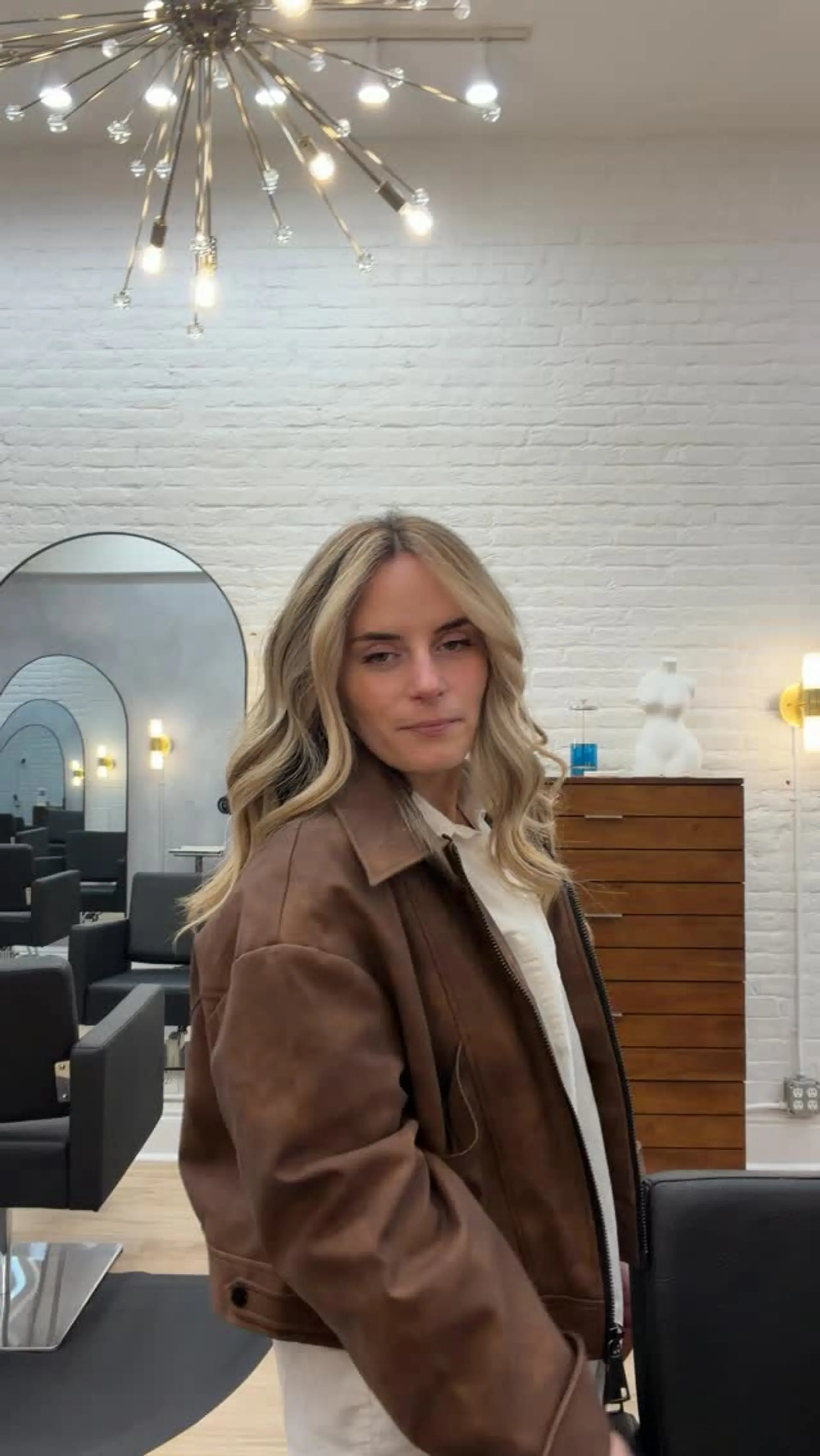 Medium-length blonde hair styled in soft waves with bright face-framing pieces and a center part. 1