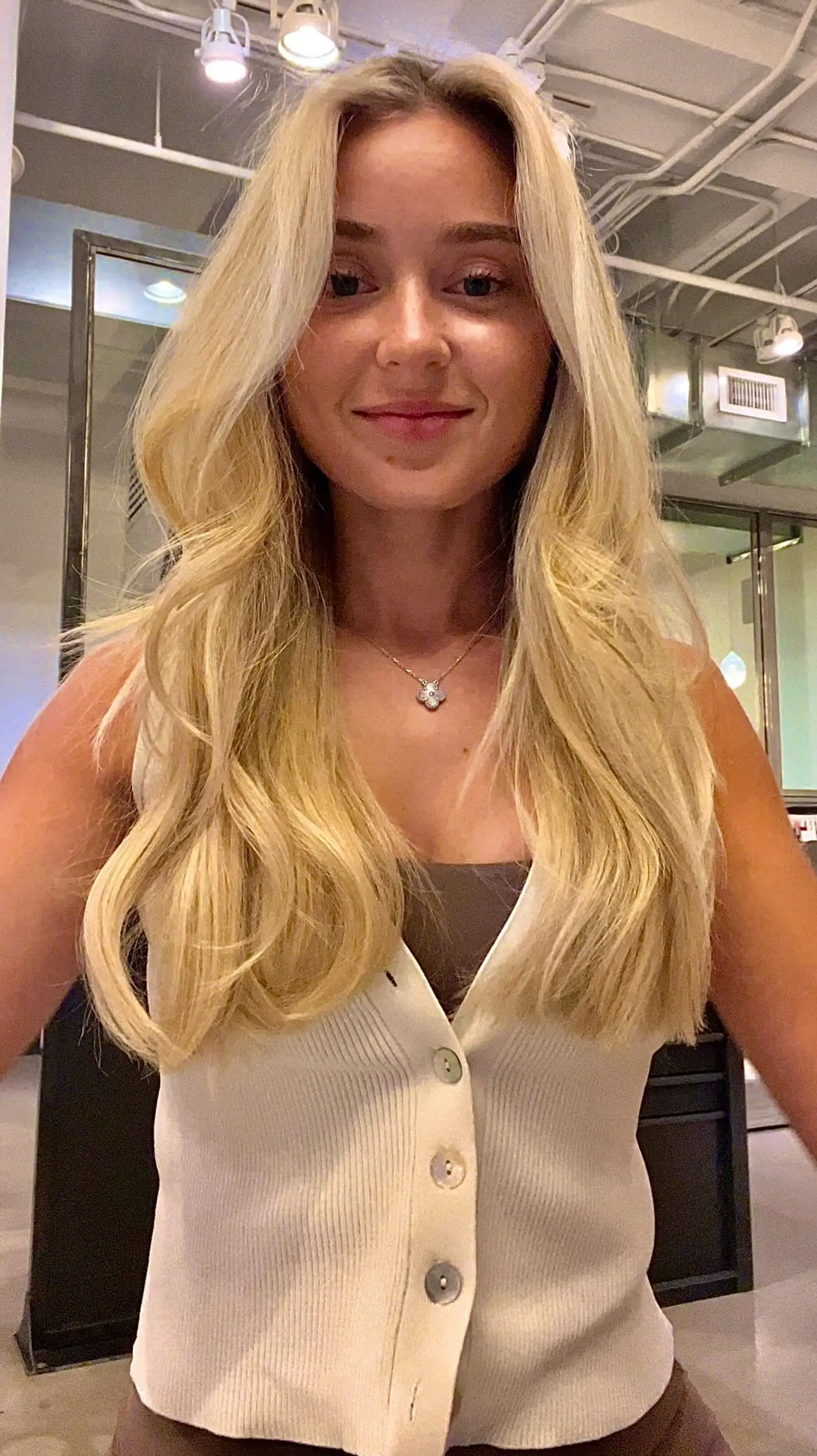 Long blonde balayage styled in loose, natural waves with face-framing layers and a soft center part. 1