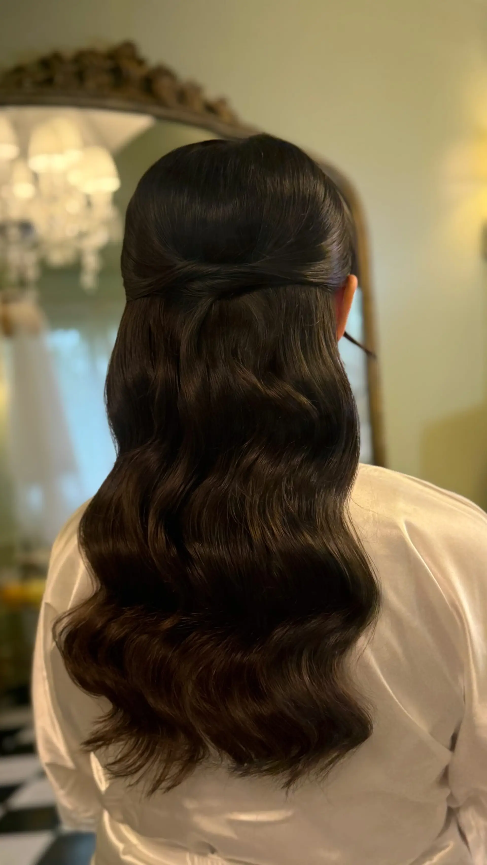 Glossy, sculpted glam waves styled into a sleek half-up twist down the back. 1