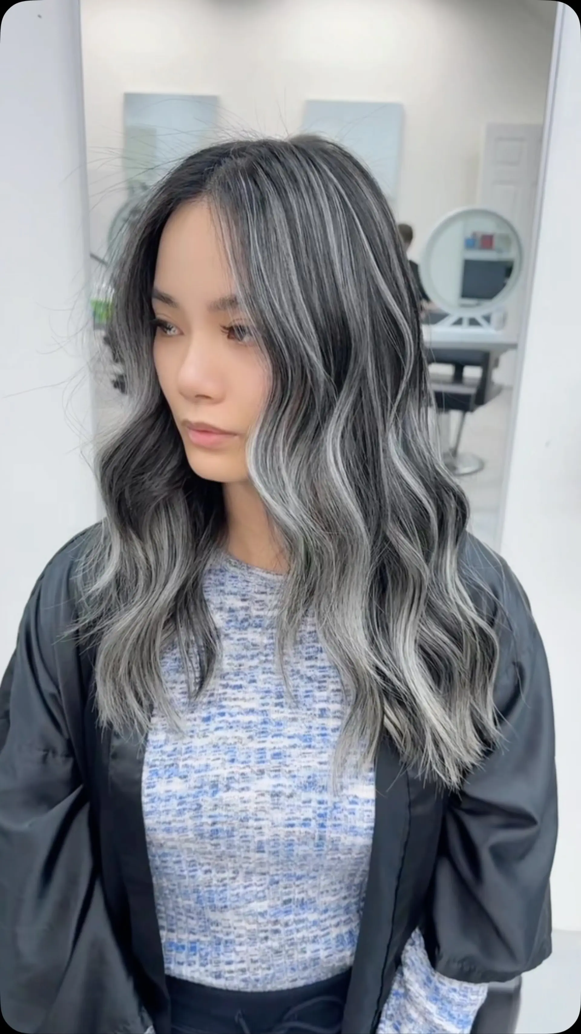 Long wavy hair with a striking ash silver and cool grey balayage over a deep dark base. 1