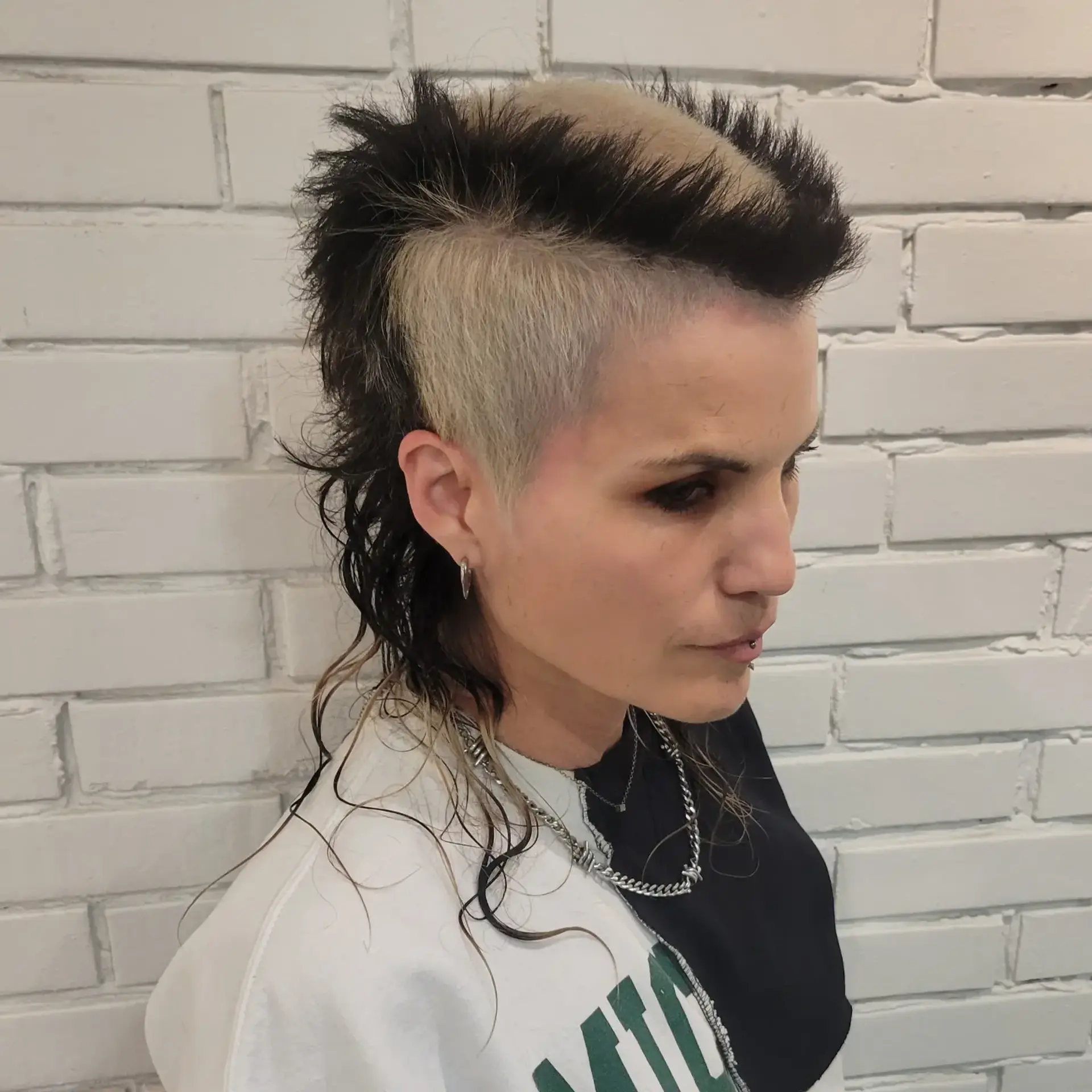 An edgy two-tone punk mullet featuring shaved platinum blonde sides with contrasting spiky black sections and longer, wispy layers at the back. 1