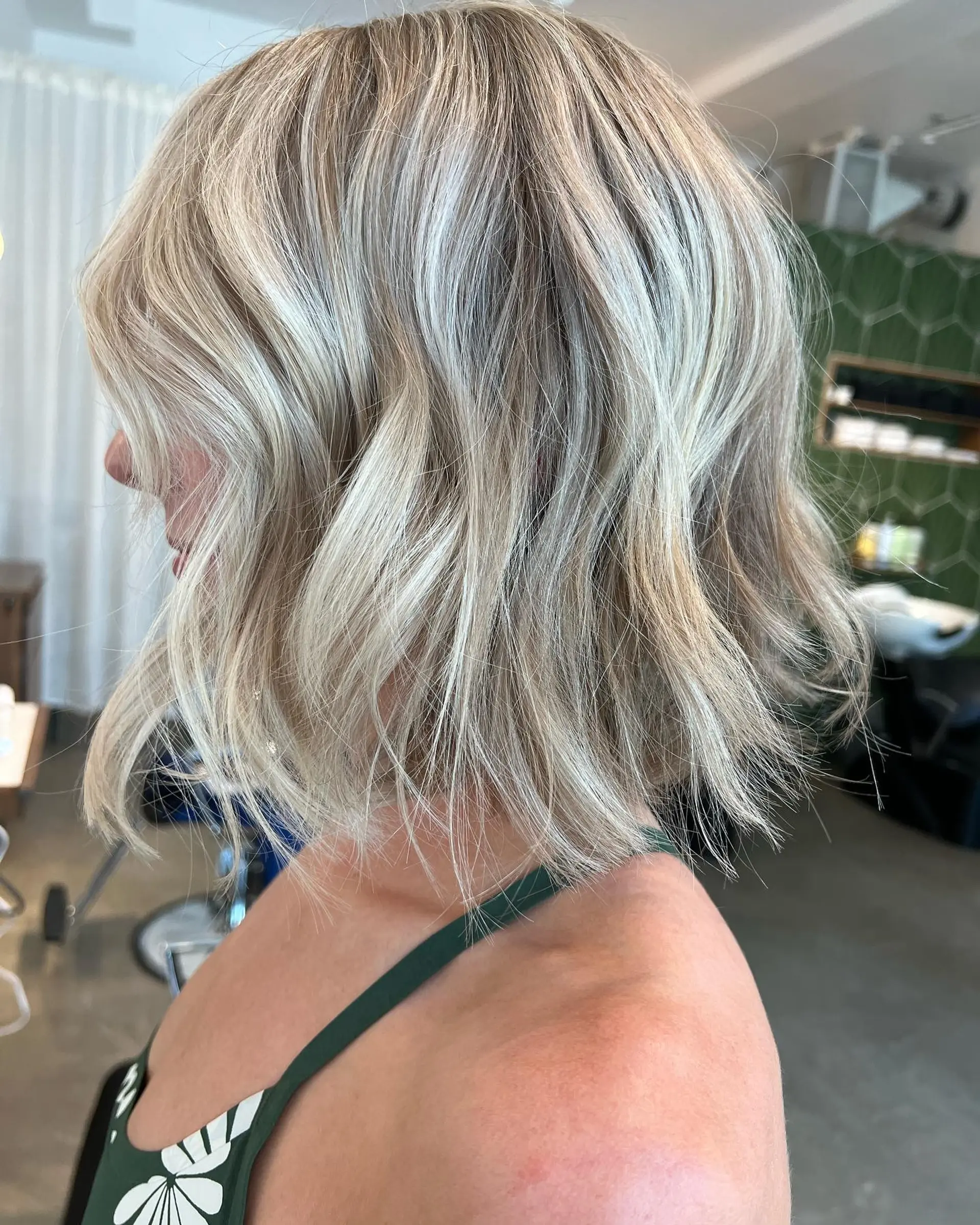 A textured chin-to-collarbone bob styled with loose beachy waves and dimensional cool blonde highlights. 1