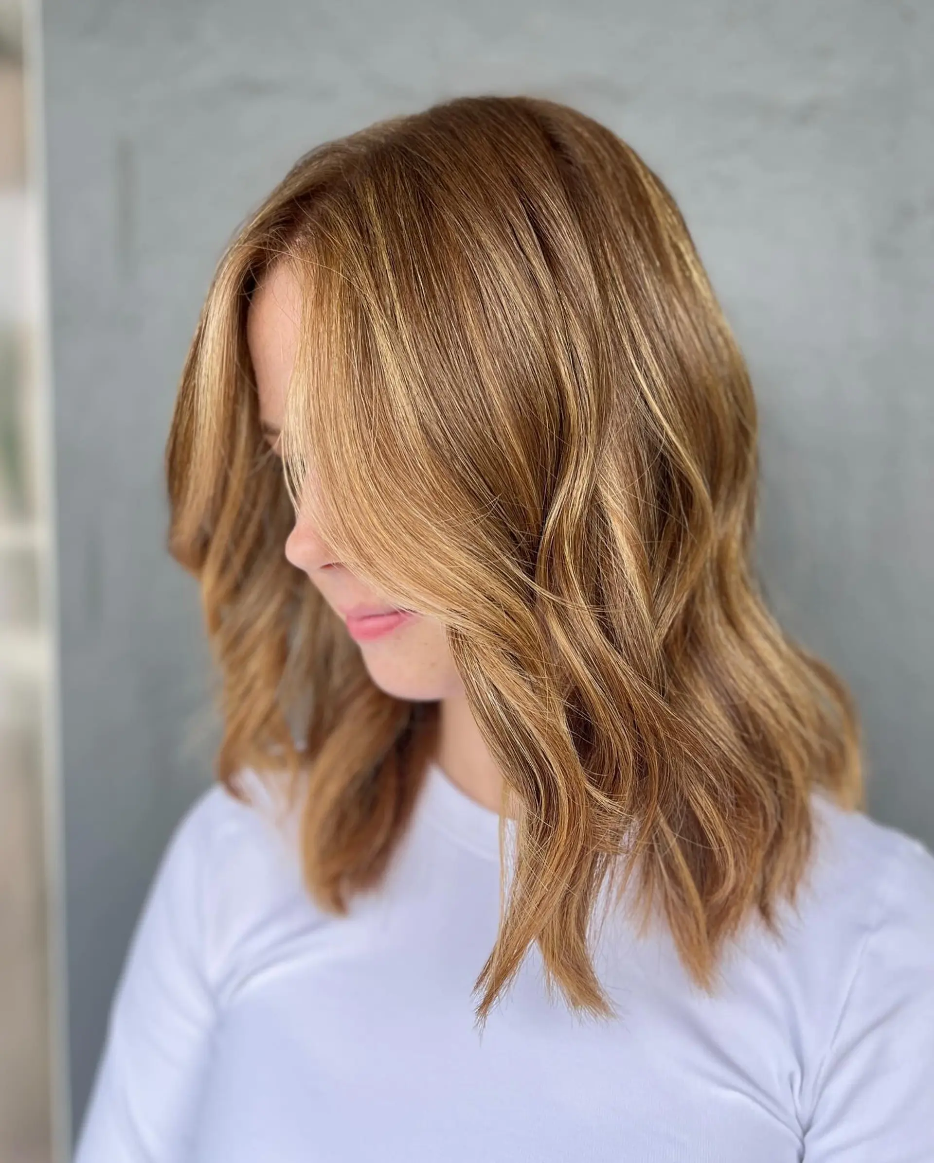 Medium-length wavy hairstyle with face-framing layers and golden blonde highlights. 1