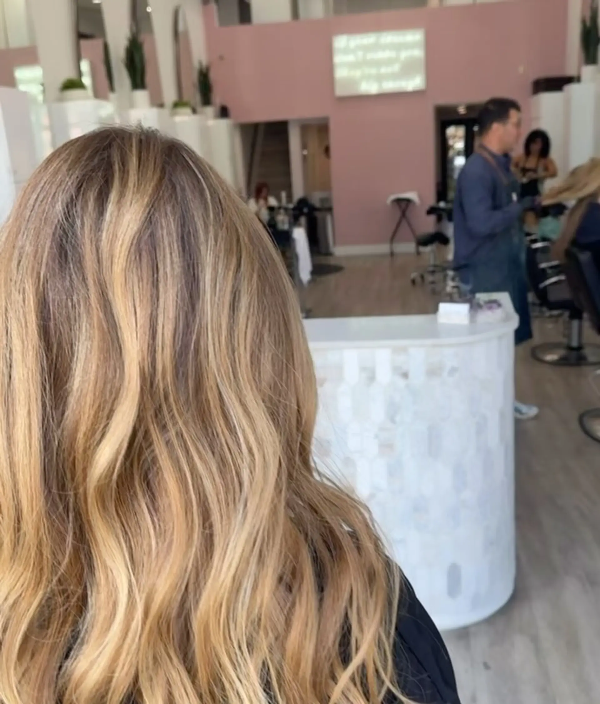 Long bronde hair featuring sun-kissed warm blonde highlights styled into loose, flowing beach waves. 1