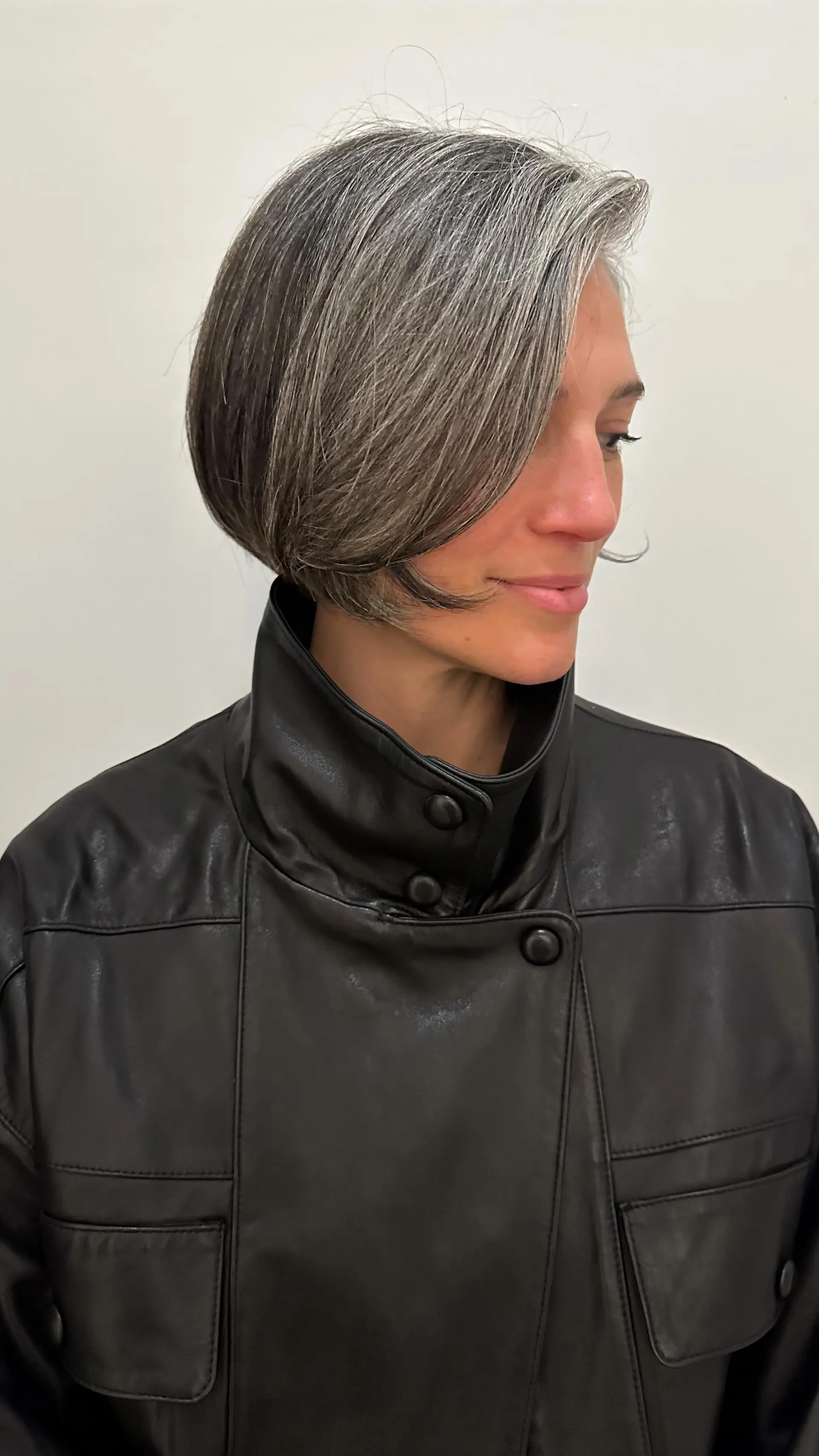 A sleek, chin-length bob featuring a side-swept fringe and showcasing natural salt-and-pepper grey hair. 1