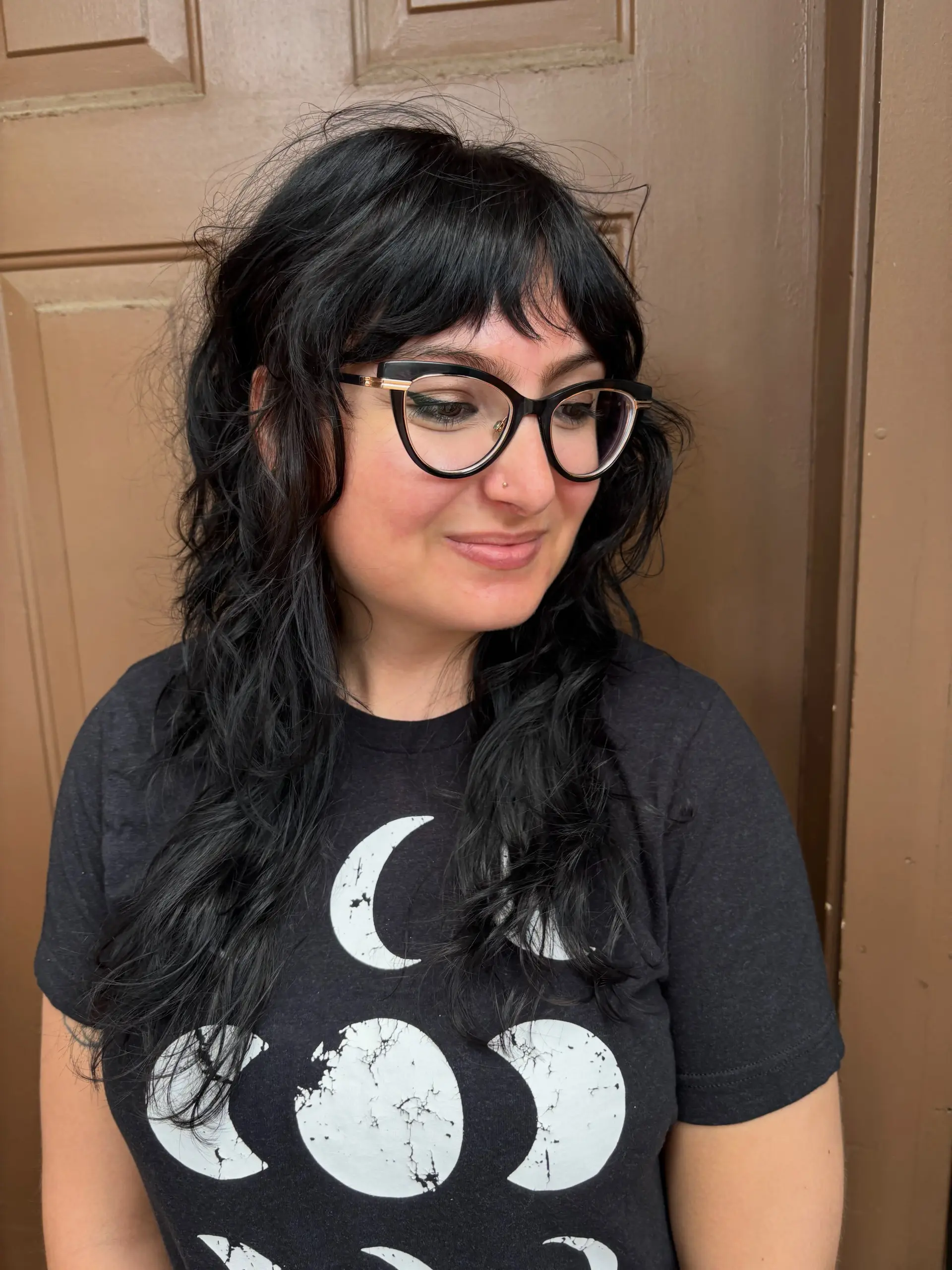 A long jet black shag haircut featuring full, piecey bangs and softly textured, wavy layers throughout. 1