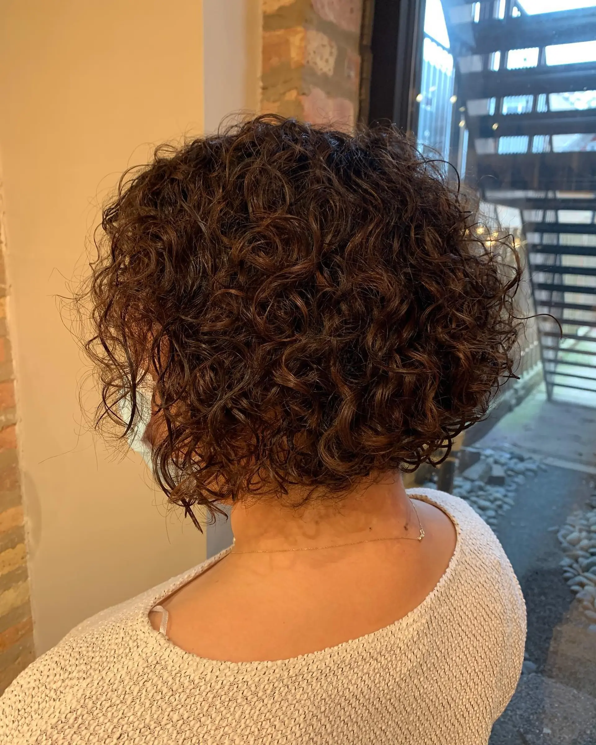 A short, curly bob with highlights to enhance the curl pattern and add dimension. 1
