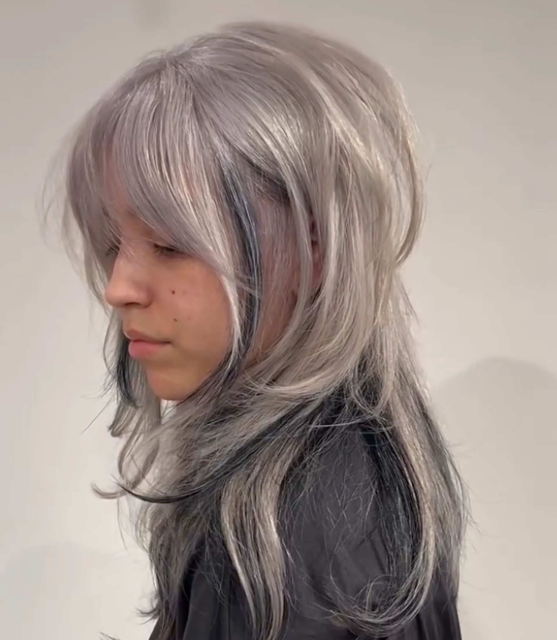 Long, wavy hair with layers, silver-to-black ombre, and wispy bangs. 1